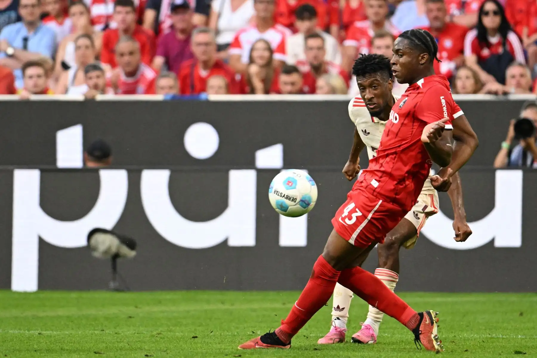El delantero francés del Bayern Munich Kingsley Coman y el defensor suizo-nigeriano del Friburgo Bruno Ogbus disputan el balón durante el partido de fútbol de la primera división alemana Bundesliga entre el FC Bayern Munich y el SC Freiburg. Foto: ANDINA/AFP