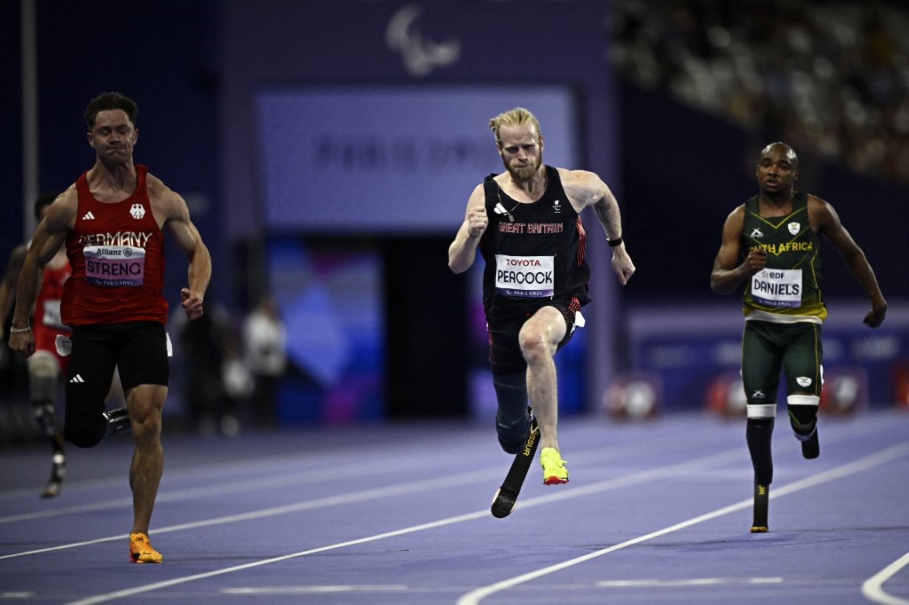 El británico Jonnie Peacock (centro) compite en la prueba masculina de 100 m T64 durante los Juegos Paralímpicos de París 2024 en el Stade de France en Saint-Denis, el 1 de septiembre de 2024. Foto: AFP