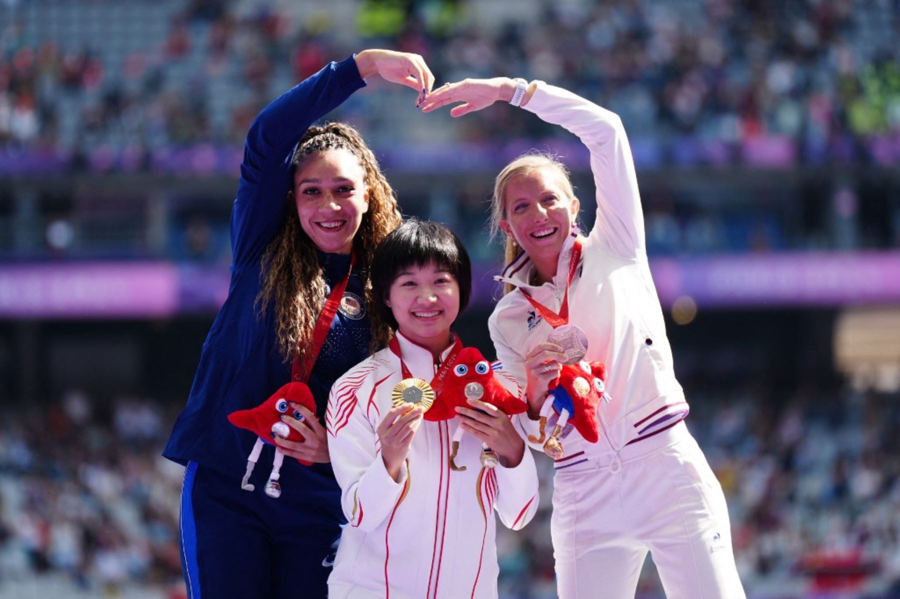 La medallista de plata estadounidense Jaleen Roberts, la medallista de oro china Wen Xiaoyan y la medallista de bronce francesa Manon Genest celebran la premiación de la final de salto de longitud T37 femenino de los Juegos Paralímpicos de París 2024 en el Stade de France,  el 2 de septiembre de 2024. Foto: AFP