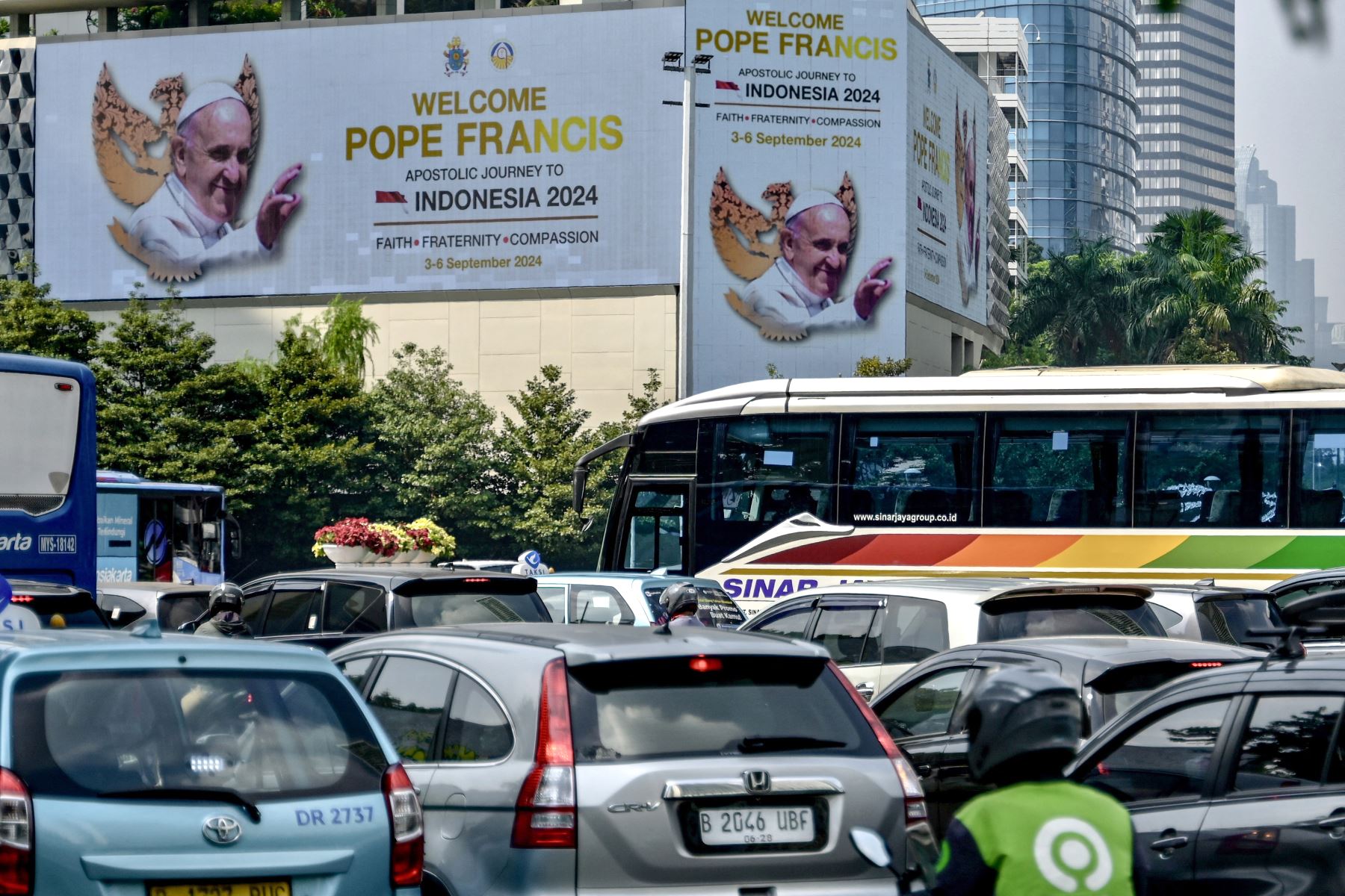 La gente conduce sus vehículos junto a vallas publicitarias gigantes que muestran un mensaje de bienvenida para el Papa Francisco en el distrito comercial de Yakarta.
Foto: AFP