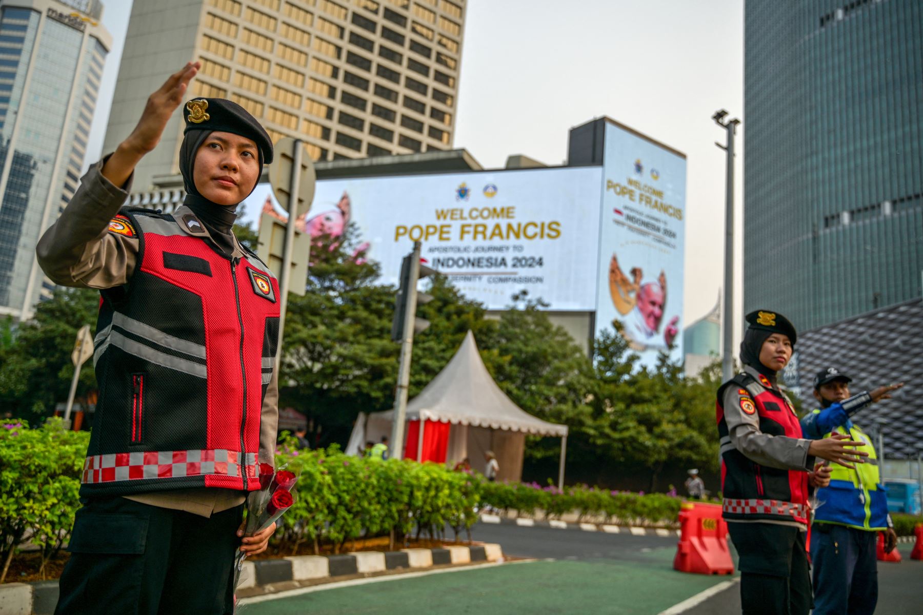 La policía indonesia dirige el tráfico junto a carteles que muestran un mensaje de bienvenida para el Papa Francisco en Yakarta.
Foto: AFP