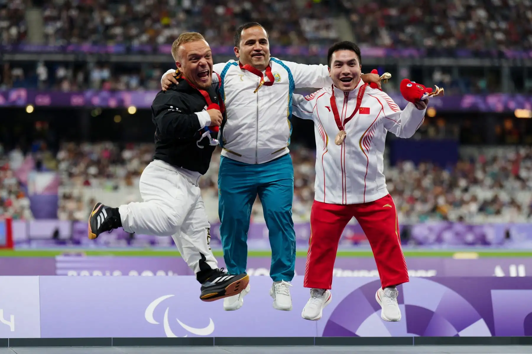 El medallista de plata alemán Niko Kappel, el medallista de oro uzbeko Bobirjon Omonov y el medallista de bronce chino Jun Huang celebran en el podio durante la ceremonia de entrega de medallas de la final de lanzamiento de bala F41 masculino en los Juegos Paralímpicos de París 2024. Foto: AFP