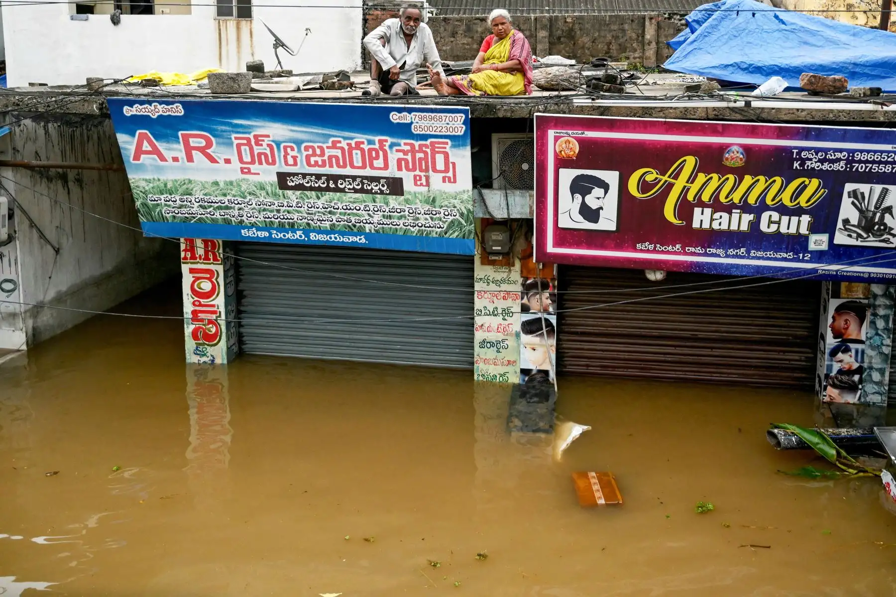 La gente se sienta en el techo de las tiendas mientras se refugia en medio de las inundaciones tras las fuertes lluvias monzónicas, en Vijayawada.
Foto: AFP