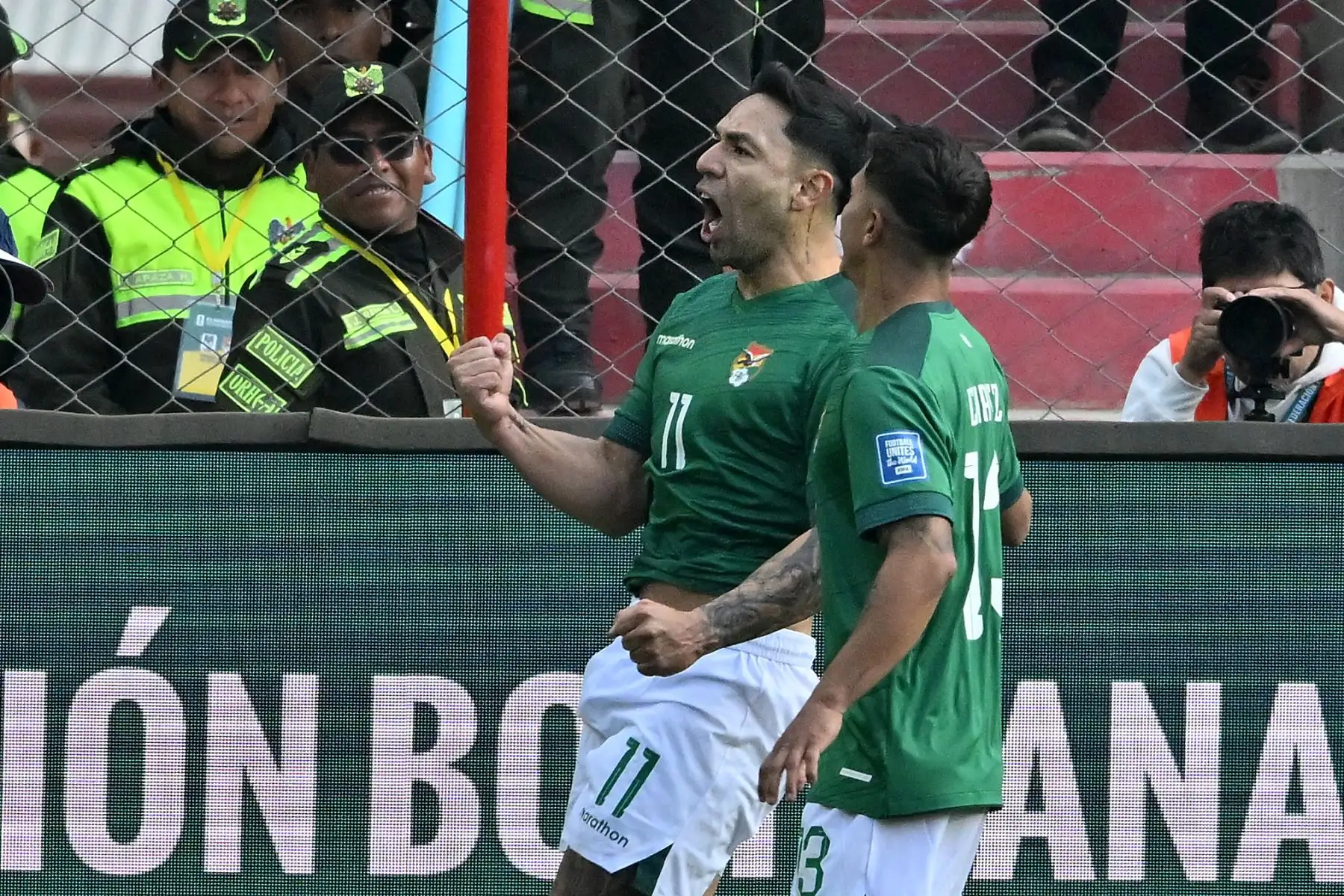 El delantero boliviano Carmelo Algarañaz (izq.) celebra con su compañero de equipo, el centrocampista Lucas Chávez, después de anotar durante el partido de fútbol de las eliminatorias sudamericanas de la Copa Mundial de la FIFA 2026 entre Bolivia y Venezuela. Foto: AFP