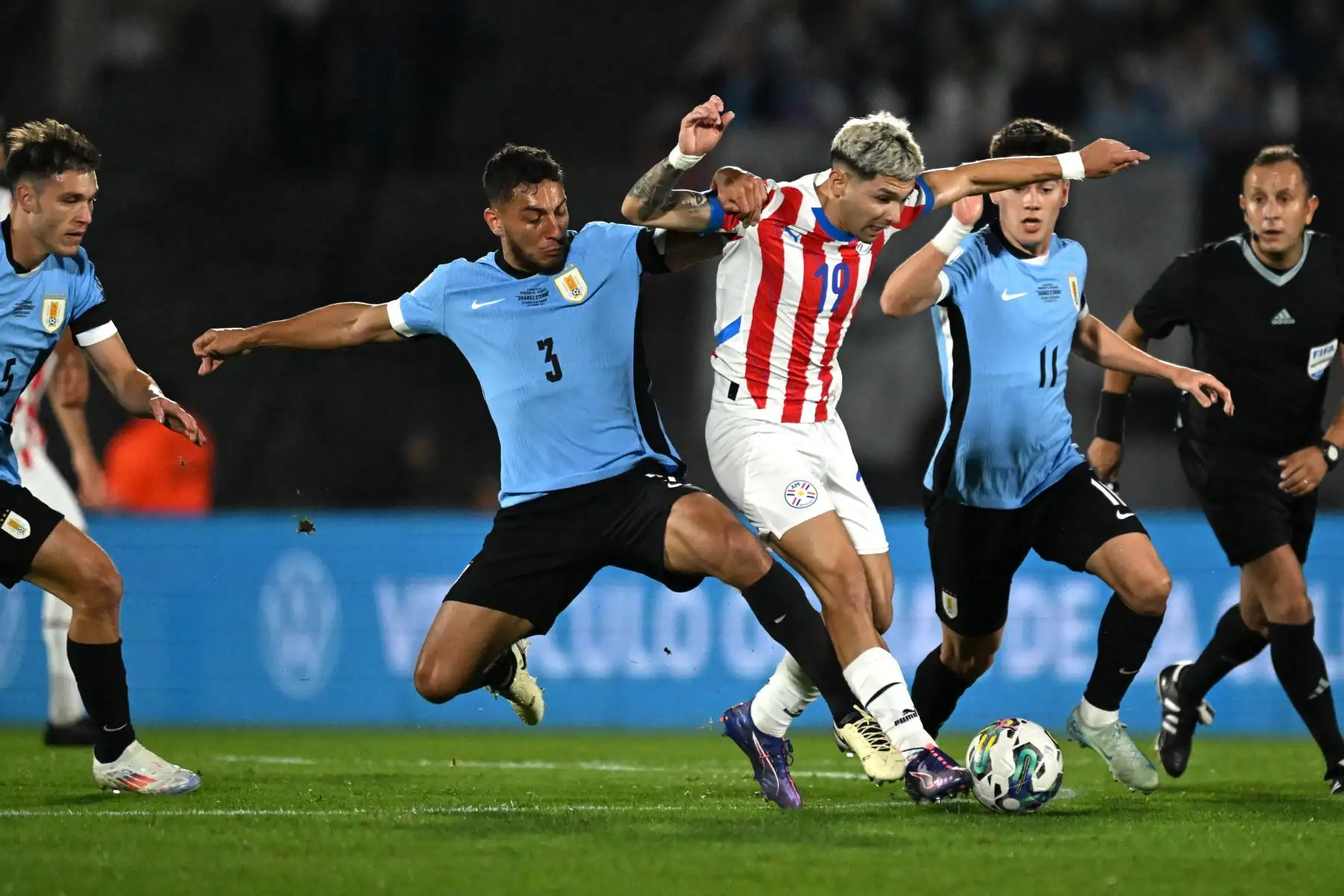 El delantero de Paraguay Julio Enciso, el defensor de Uruguay Sebastián Cáceres y el mediocampista de Uruguay Facundo Pellistri luchan por el balón durante el partido de fútbol de las Eliminatorias Sudamericanas de la Copa Mundial FIFA 2026 entre Uruguay y Paraguay en el estadio Centenario de Montevideo. Foto: AFP