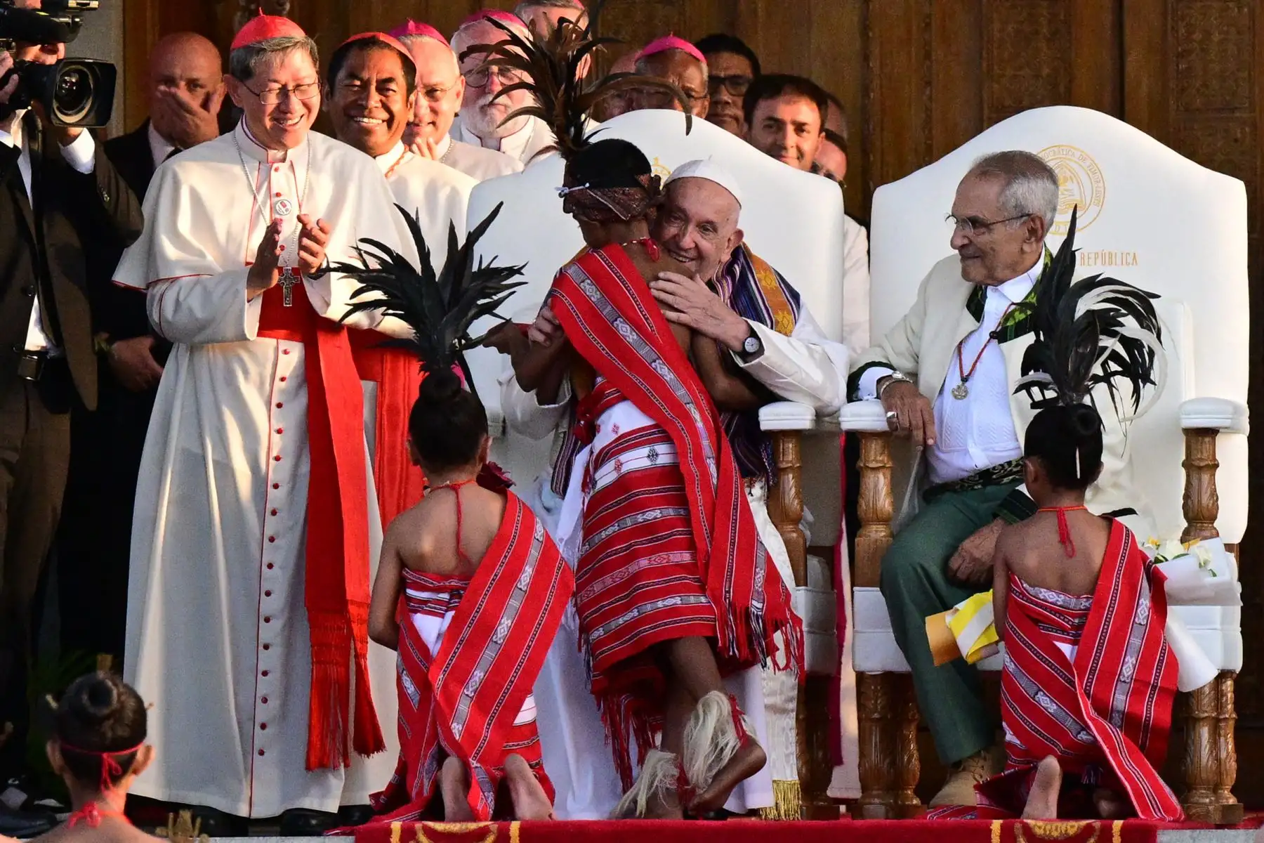 El papa Francisco, sentado junto al presidente de Timor Oriental, José Ramos-Horta, saluda a los niños con atuendos tradicionales durante su ceremonia de bienvenida en el Palacio Presidencial de Dili. Foto: AFP
