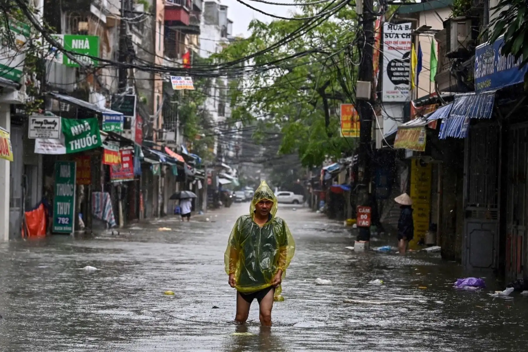 Un hombre con un poncho de plástico camina entre las aguas de la inundación en una calle de Hanoi luego de que las fuertes lluvias del tifón Yagi provocaran inundaciones en el norte de Vietnam. Foto: AFP