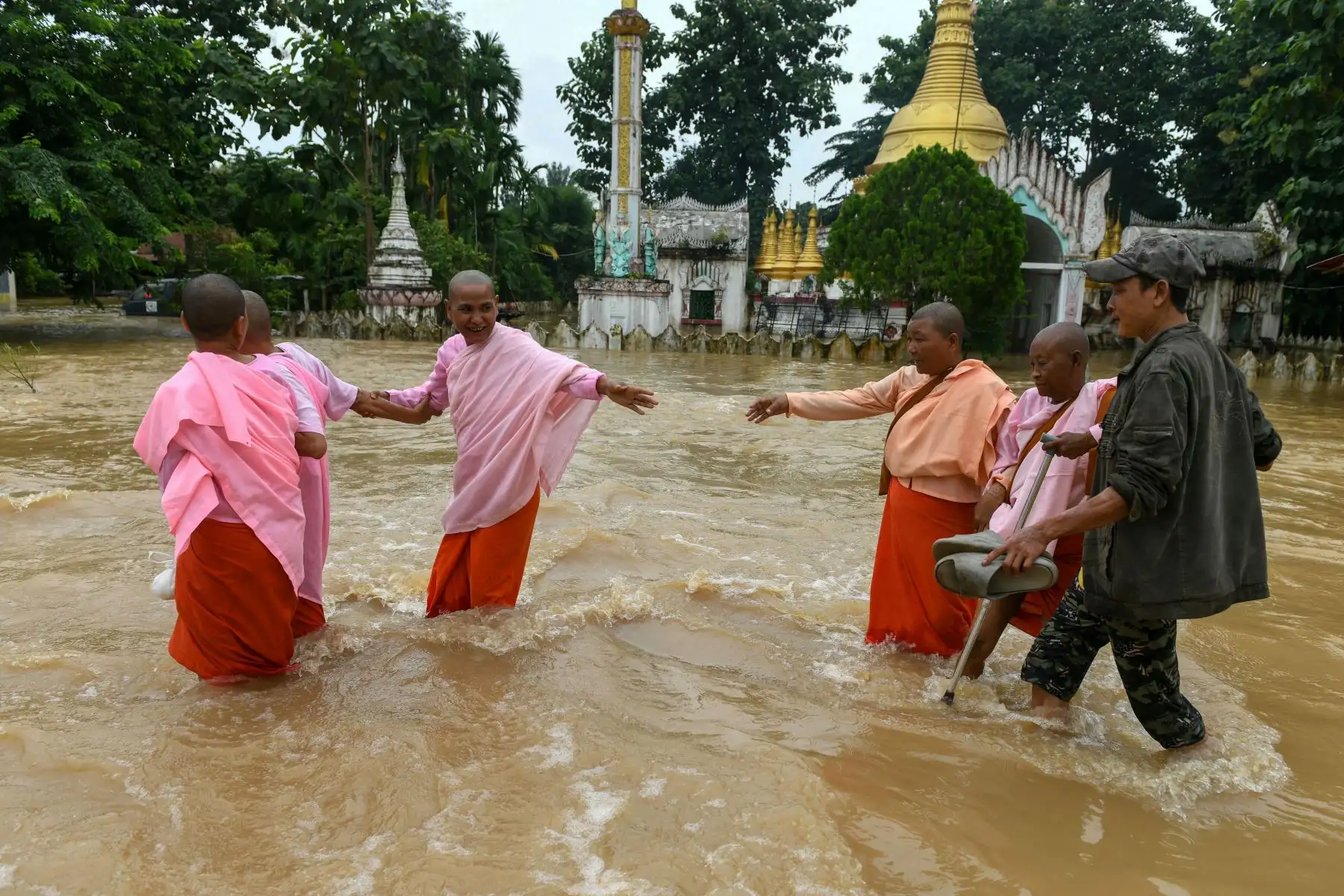 Monjas budistas caminan por las aguas de la inundación junto a un templo en Taungoo, en la región de Bago, en Myanmar, el 14 de septiembre de 2024, tras las fuertes lluvias que siguieron al paso del tifón Yagi. El tifón Yagi provocó un colosal diluvio de lluvia que inundó una franja del norte de Vietnam. Foto: ANDINA/AFP