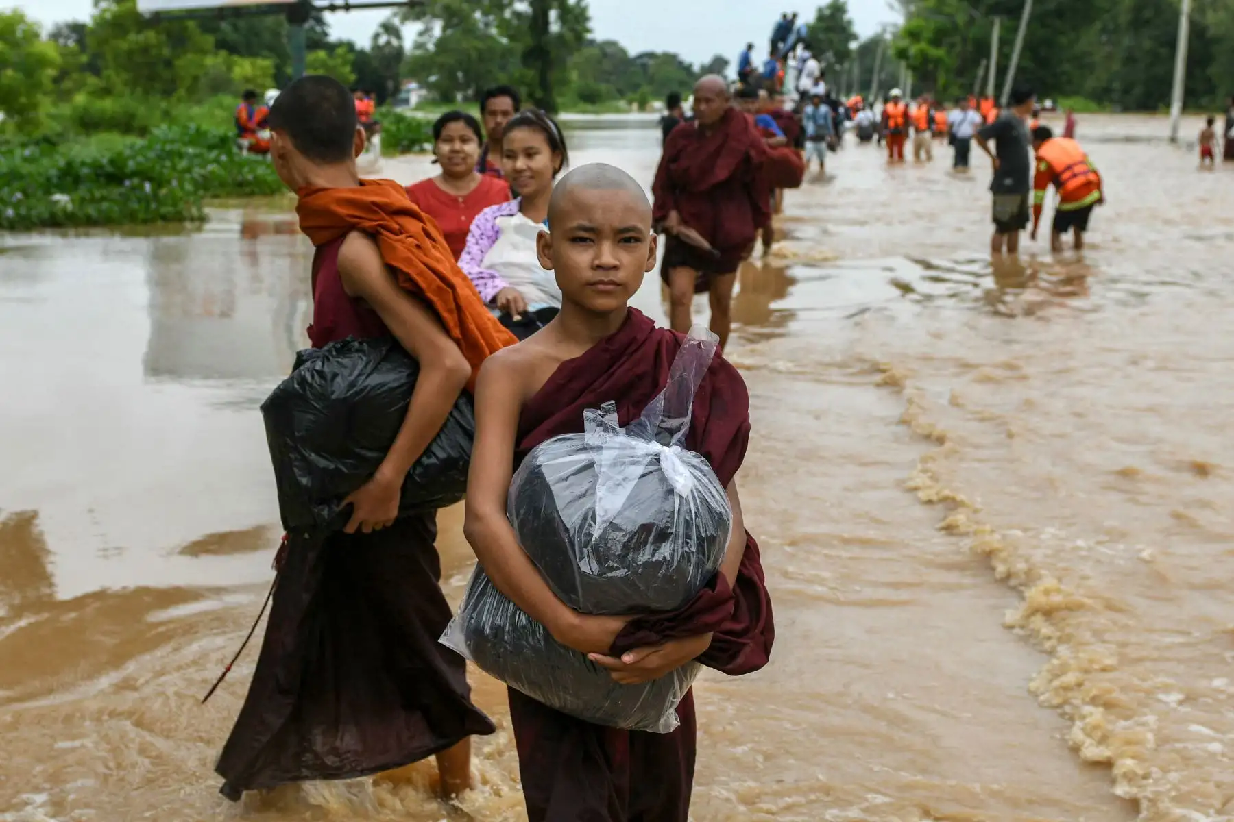Un joven monje budista lleva sus pertenencias mientras camina por las aguas de la inundación en Taungoo, en la región de Bago, en Myanmar, el 14 de septiembre de 2024, tras las fuertes lluvias provocadas por el tifón Yagi. El tifón Yagi provocó un diluvio colosal que inundó una franja del norte de Vietnam. Foto. ANDINA/AFP