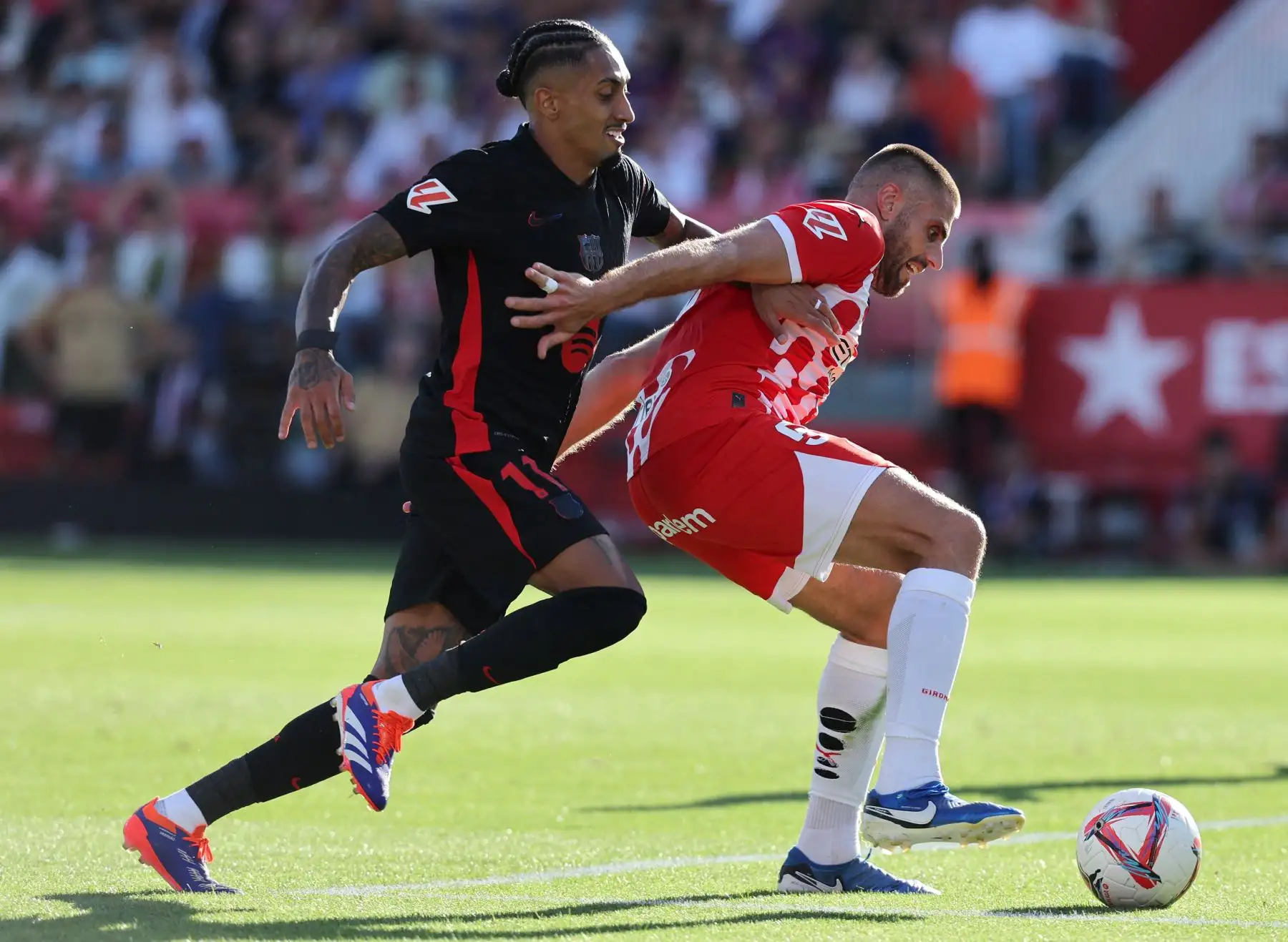 El defensa español del Girona, David López, lucha por el balón con el delantero brasileño del Barcelona, ​​Raphinha, durante el partido de fútbol de la liga española entre el Girona FC y el FC Barcelona. Foto: ANDINA/AFP