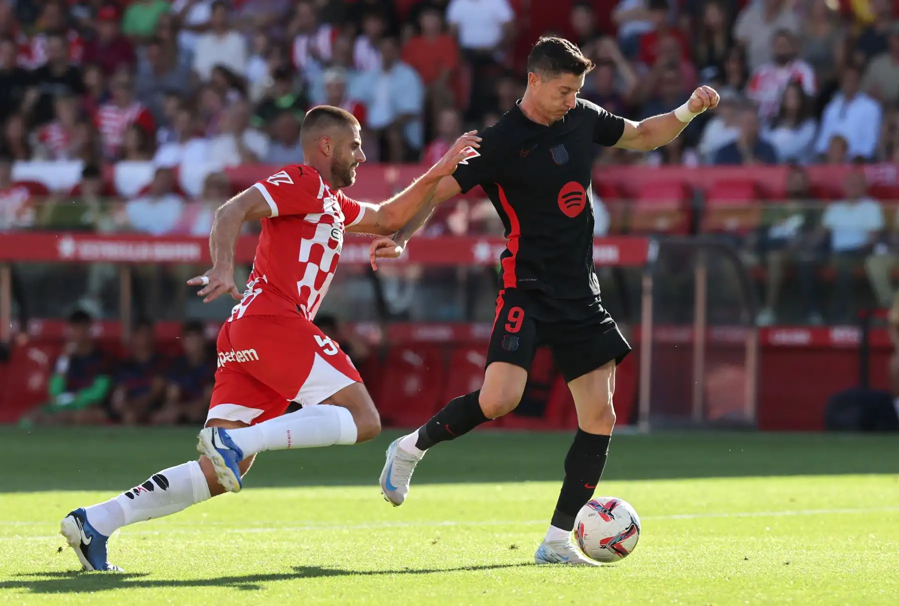 El delantero polaco del Barcelona, ​​Robert Lewandowski, lucha por el balón con el defensa español del Girona, David López, durante el partido de fútbol de la liga española entre el Girona FC y el FC Barcelona. Foto: ANDINA/AFP