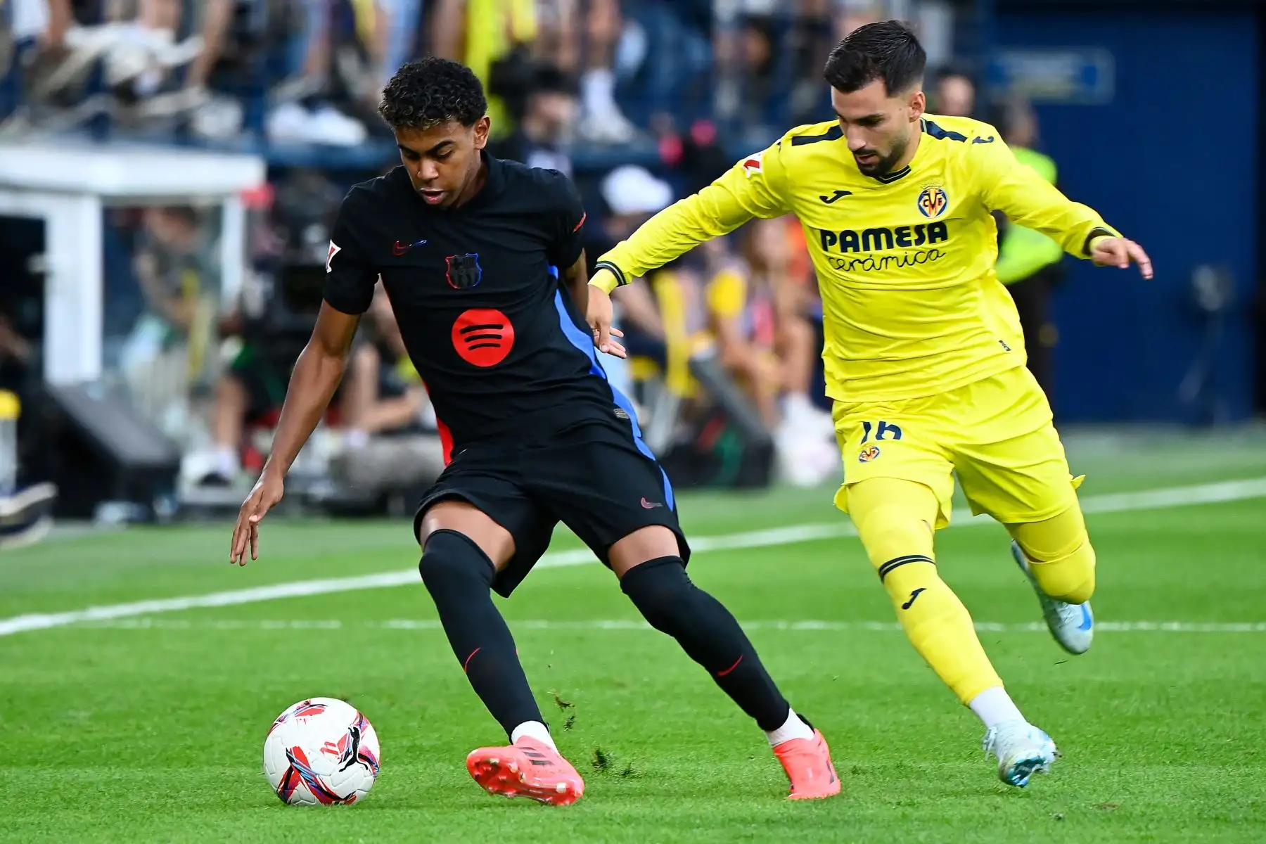 El delantero español del Barcelona, ​​Lamine Yamal, lucha por el balón con el centrocampista español del Villarreal, Alex Baena, durante el partido de fútbol de la liga española entre el Villarreal CF y el FC Barcelona. Foto: ANDINA/AFP