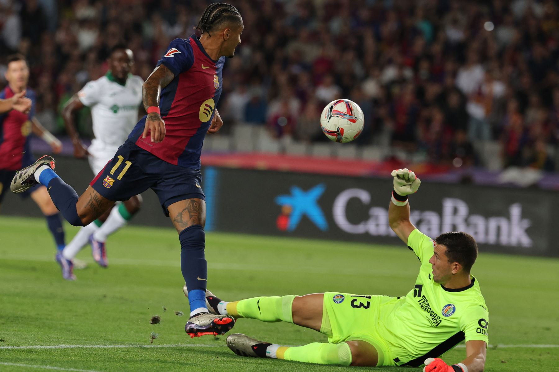 El delantero brasileño del Barcelona, Raphinha, lucha por el balón con el portero español del Getafe, David Soria, durante el partido de fútbol de la liga española entre el FC Barcelona y el Getafe CF en el Estadi Olimpic Lluis Companys de Barcelona el 25 de septiembre de 2024. Foto: AFP