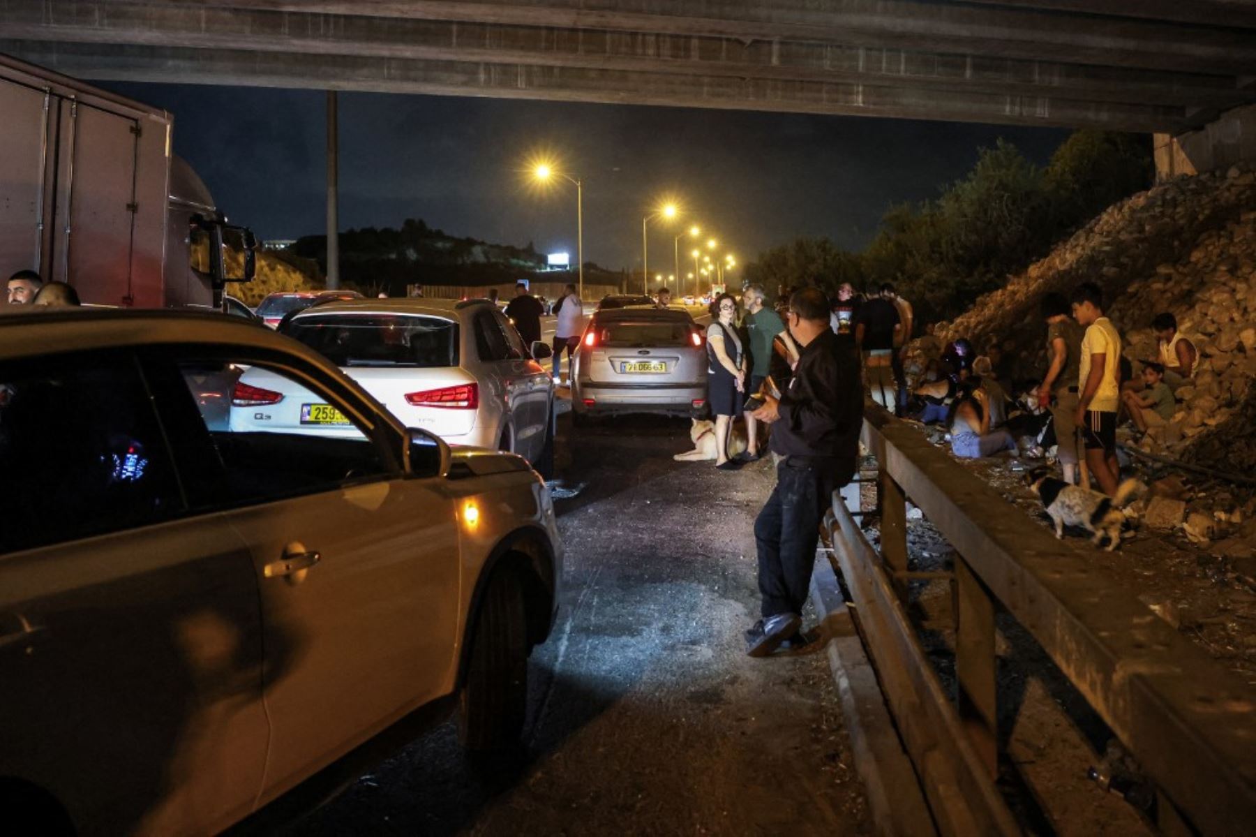 La gente se cubre con vehículos debajo de un puente a lo largo de una carretera entre Kafr Qara y Baqa al-Gharbiya en el norte de Israel. Foto: AFP