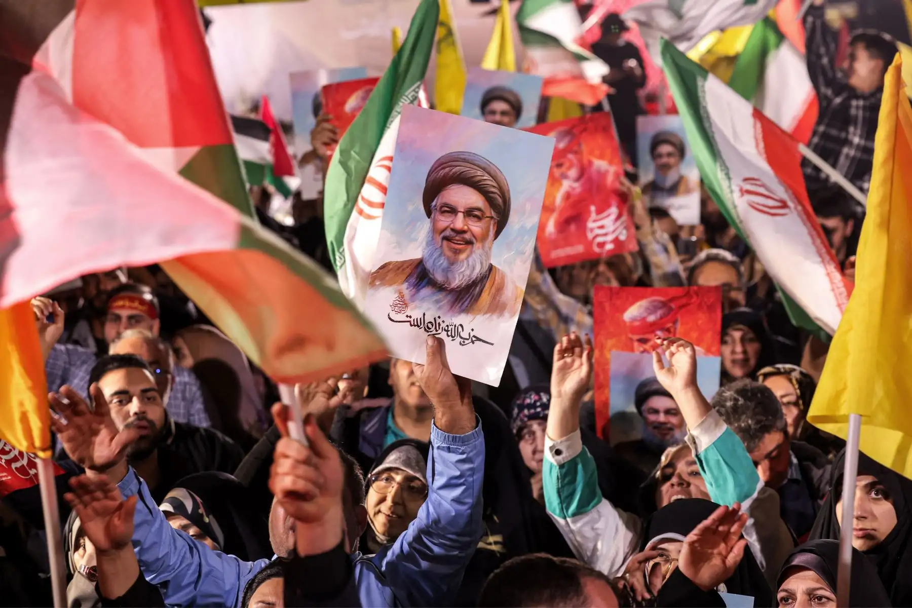 Un manifestante sostiene un cartel que muestra el rostro del líder asesinado del grupo libanés Hezbollah, Hassan Nasrallah, con el lema persa "Hezbollah está vivo", durante una manifestación que celebra después de que Irán lanzara una andanada de misiles contra Israel en respuesta a los asesinatos de Nasrallah y otros Irán. Militantes respaldados por Irán frente a la mezquita Imam Jaafar Sadiq en la Plaza Palestina de Teherán el 1 de octubre de 2024. Los informes dicen que Irán disparó entre 150 y 200 misil