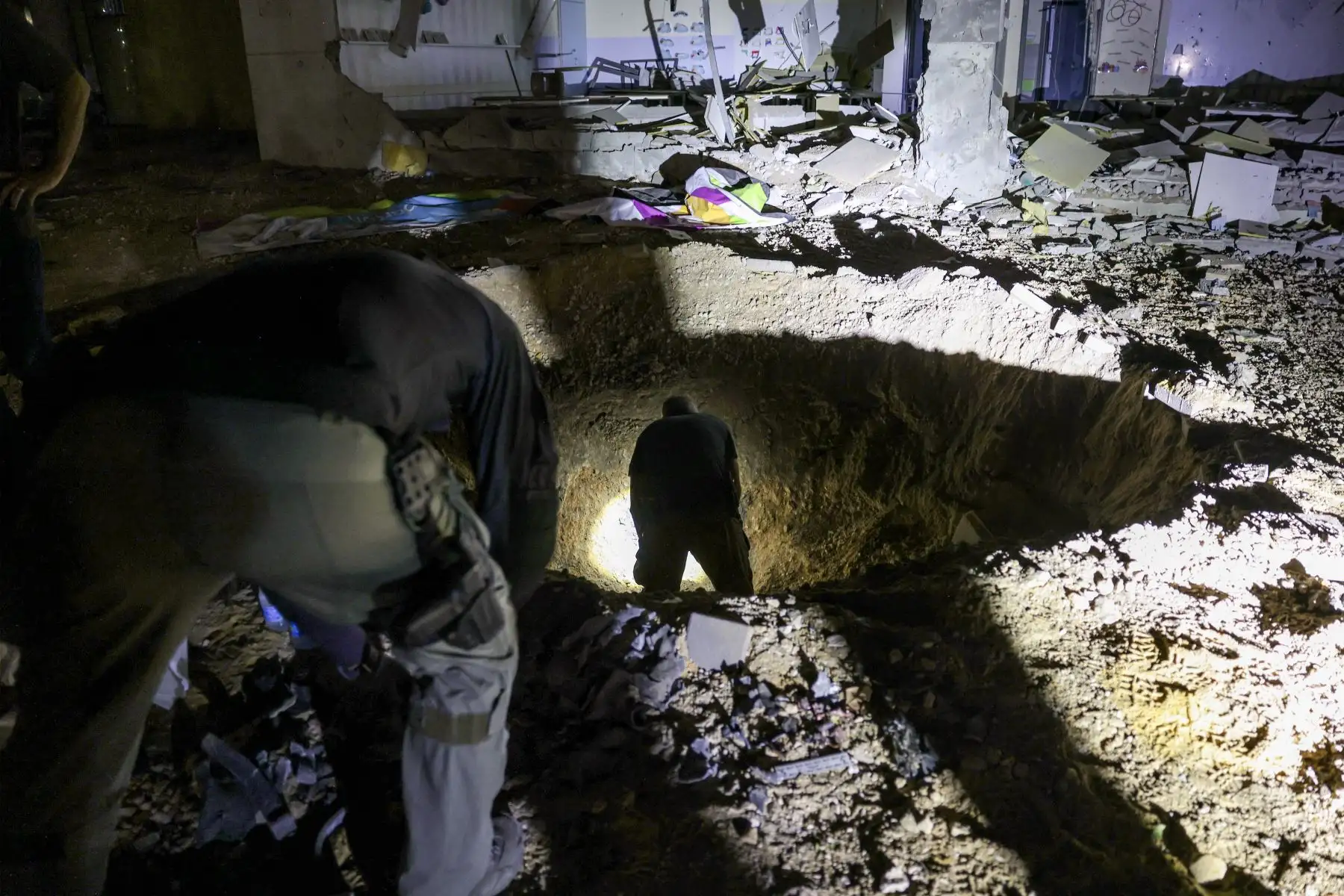 Miembros del Comando del Frente Interior de Israel y las fuerzas policiales inspeccionan un cráter dejado por un proyectil que explotó en un edificio escolar muy dañado en la ciudad de Gedera, en el sur de Israel, el 1 de octubre de 2024, después de que Irán lanzara una andanada de misiles contra Israel en respuesta a los asesinatos. del líder libanés de Hezbollah, Nasrallah, y otros militantes respaldados por Irán. Los informes dicen que Irán disparó entre 150 y 200 misiles en el ataque, el segundo del paí