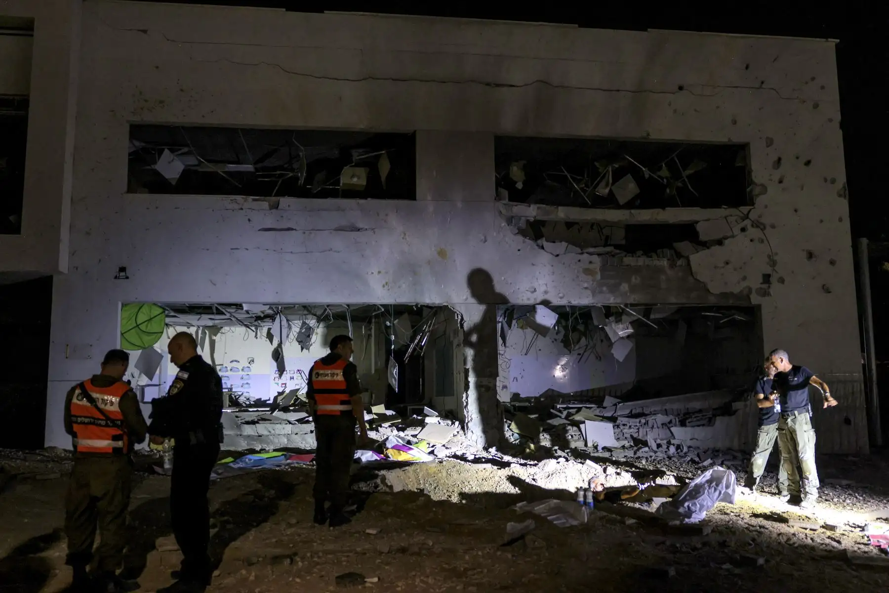 Miembros del Comando del Frente Interior de Israel y las fuerzas policiales inspeccionan un cráter dejado por un proyectil que explotó en un edificio escolar muy dañado en la ciudad de Gedera, en el sur de Israel, el 1 de octubre de 2024, después de que Irán lanzara una andanada de misiles contra Israel en respuesta a los asesinatos. del líder libanés de Hezbollah, Nasrallah, y otros militantes respaldados por Irán. Los informes dicen que Irán disparó entre 150 y 200 misiles en el ataque, el segundo del paí