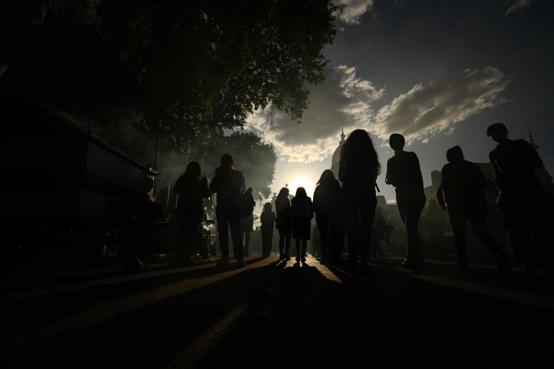 Personas caminan por una calle durante el eclipse anular solar en Buenos Aires. Parte del hemisferio sur fue testigo este miércoles de un eclipse anular que ocurre cuando la Luna cubra casi totalmente al Sol, dejando visible un anillo luminoso , un espectáculo que se vió en su máximo esplendor desde la Patagonia chilena y argentina. AFP