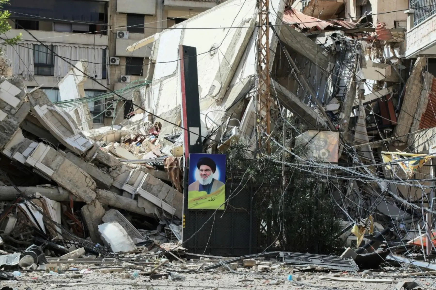 Una fotografía tomada por la oficina de medios de Hezbollah el 2 de octubre de 2024 muestra un retrato del líder asesinado del grupo, Hassan Nasrallah, colgado de los escombros de un edificio destruido en un ataque aéreo israelí en un vecindario en los suburbios del sur de Beirut. Foto: AFP