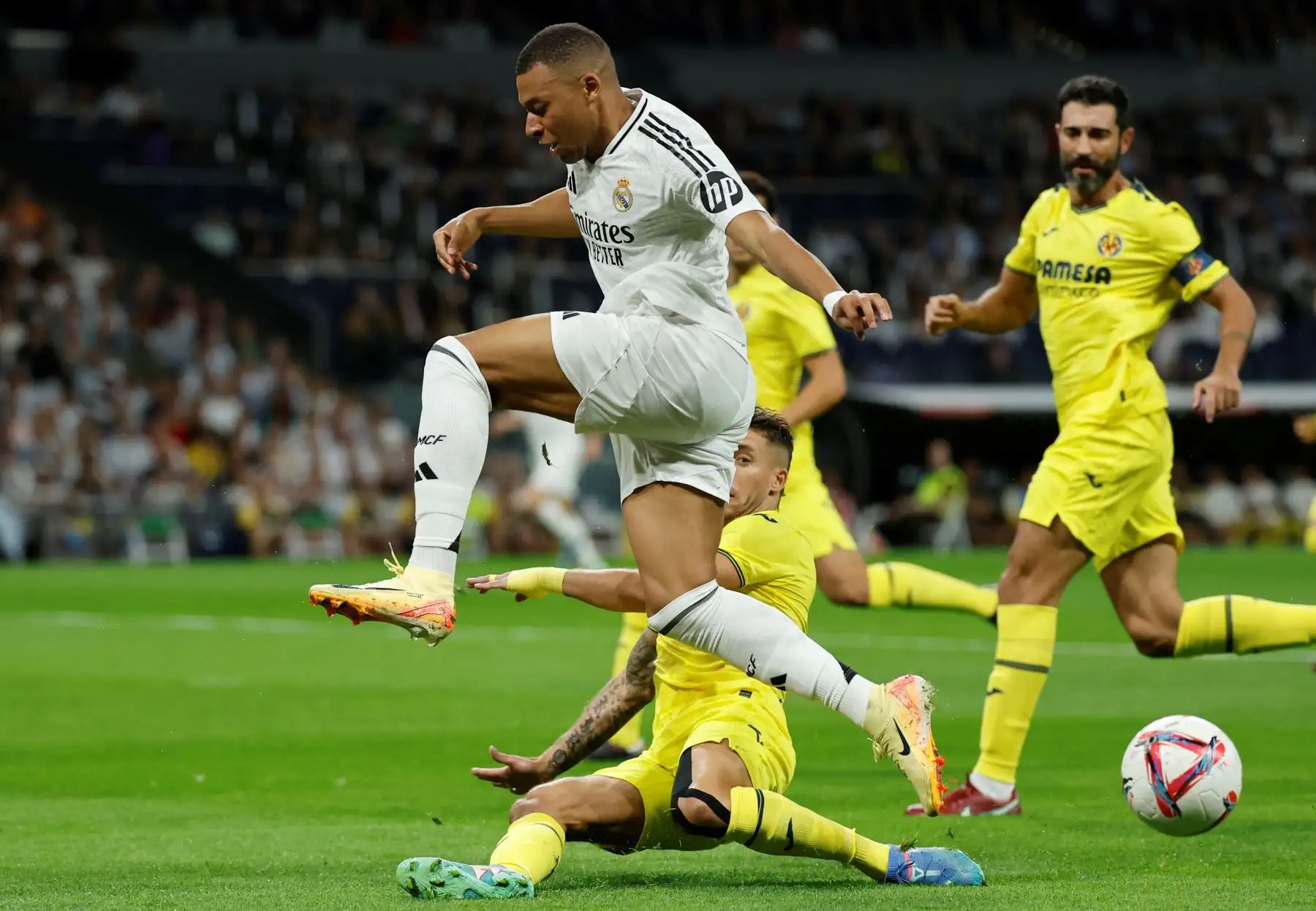 El delantero francés del Real Madrid, Kylian Mbappé, lucha por el balón con el defensa español del Villarreal, Kiko Femenia, durante el partido de fútbol de la liga española entre el Real Madrid CF y el Villarreal CF en el estadio Santiago Bernabéu de Madrid. Foto: ANDINA/ AFP