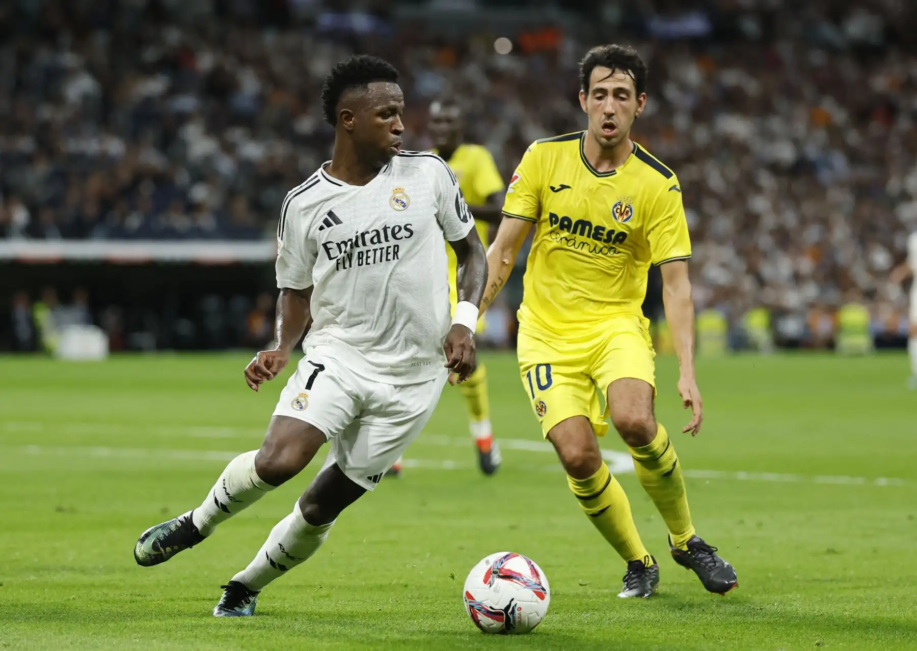 El delantero brasileño del Real Madrid, Vinicius Junior, lucha por el balón con el centrocampista español del Villarreal, Daniel Parejo, durante el partido de fútbol de la liga española entre el Real Madrid CF y el Villarreal CF en el estadio Santiago Bernabéu de Madrid. Foto: ANDINA/AFP