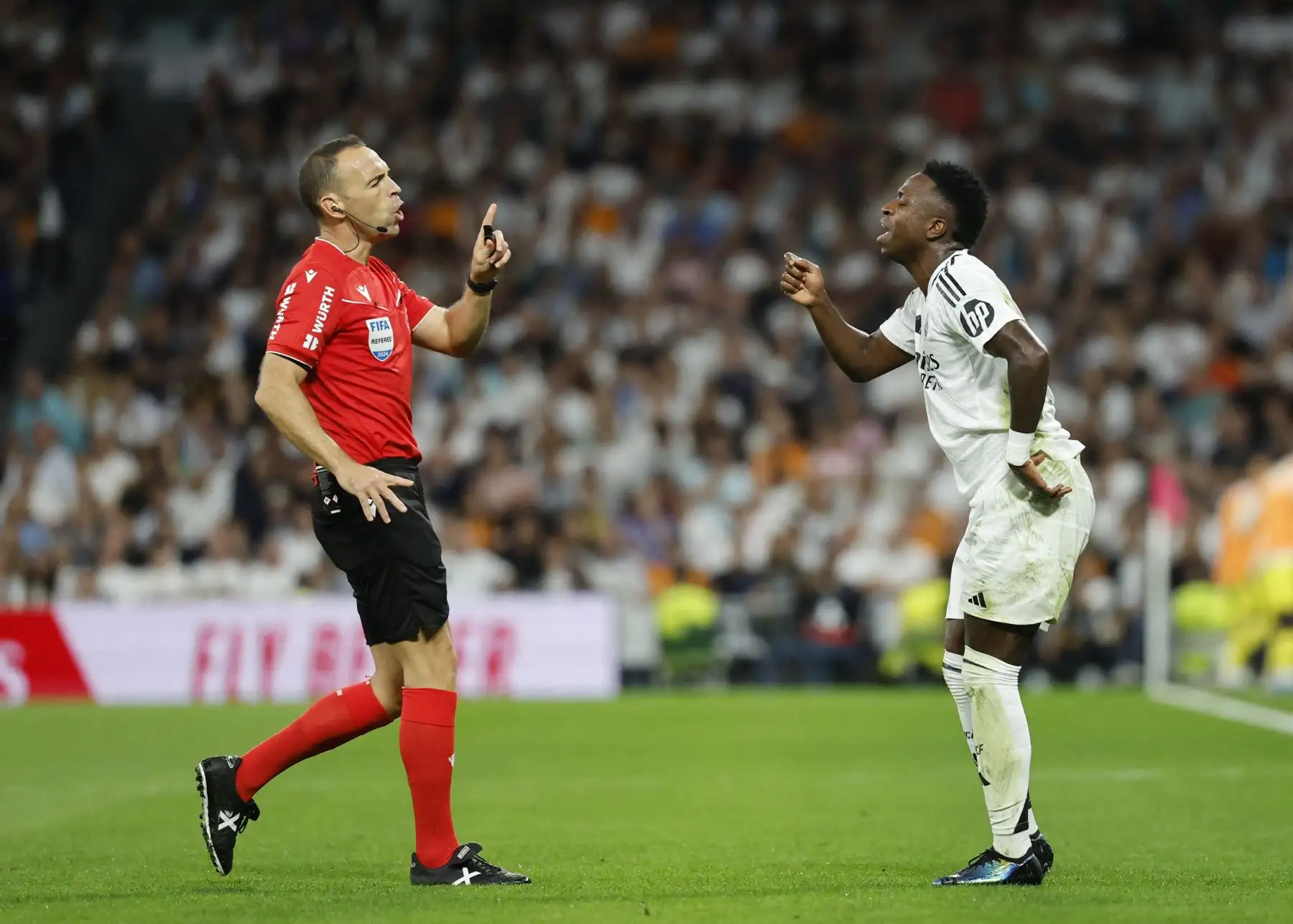 El delantero brasileño del Real Madrid, Vinicius Junior, habla con el árbitro español Guillermo Cuadra durante el partido de fútbol de la liga española entre el Real Madrid CF y el Villarreal CF en el estadio Santiago Bernabéu de Madrid.
Foto: ANDINA/ AFP