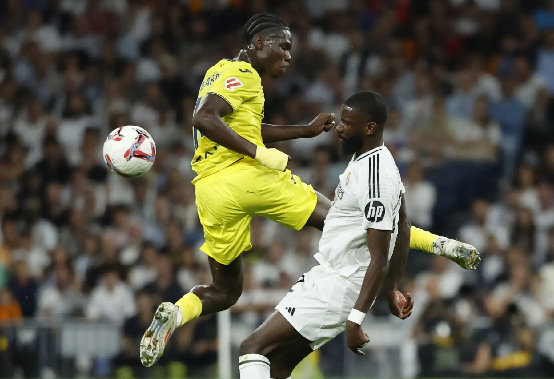 El defensa alemán del Real Madrid, Antonio Ruediger, lucha por el balón con el centrocampista senegalés del Villarreal, Pape Gueye, durante el partido de fútbol de la liga española entre el Real Madrid CF y el Villarreal CF en el estadio Santiago Bernabéu de Madrid. Foto: ANDINA/AFP