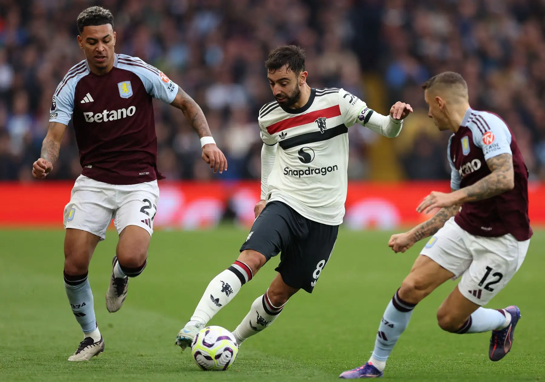 El centrocampista inglés del Aston Villa #27 Morgan Rogers (L) y el defensor francés del Aston Villa #12 Lucas Digne (R) compiten con el centrocampista portugués del Manchester United #08 Bruno Fernandes durante el partido de fútbol de la Premier League inglesa entre el Aston Villa y el Manchester United. AFP