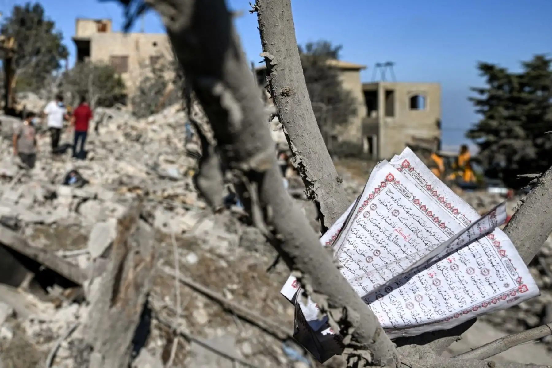 Páginas de una copia del Corán, el libro sagrado del Islam, se aferran a las ramas de un árbol en el lugar de un previo ataque aéreo israelí contra la aldea de Aito, en el norte del Líbano. Foto: AFP