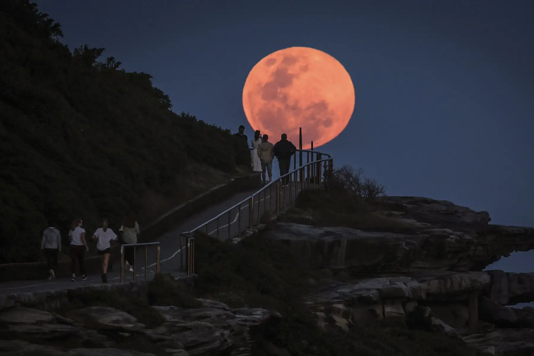 Una superluna sale detrás de personas que se encuentran en un promontorio cerca de la playa Bondi de Sydney, Australia.

Foto:AFP