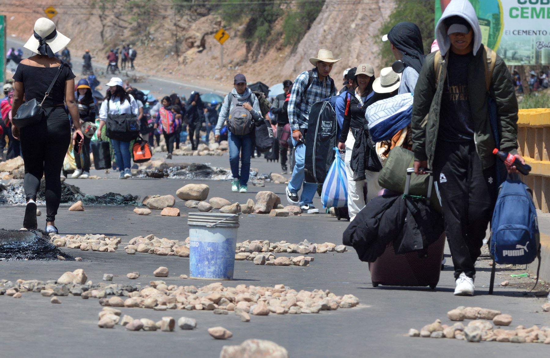 Los pasajeros caminan por una carretera que va de Santa Cruz a La Paz bloqueada por partidarios del expresidente boliviano Evo Morales en Parotani, Bolivia. Foto: ANDINA/AFP