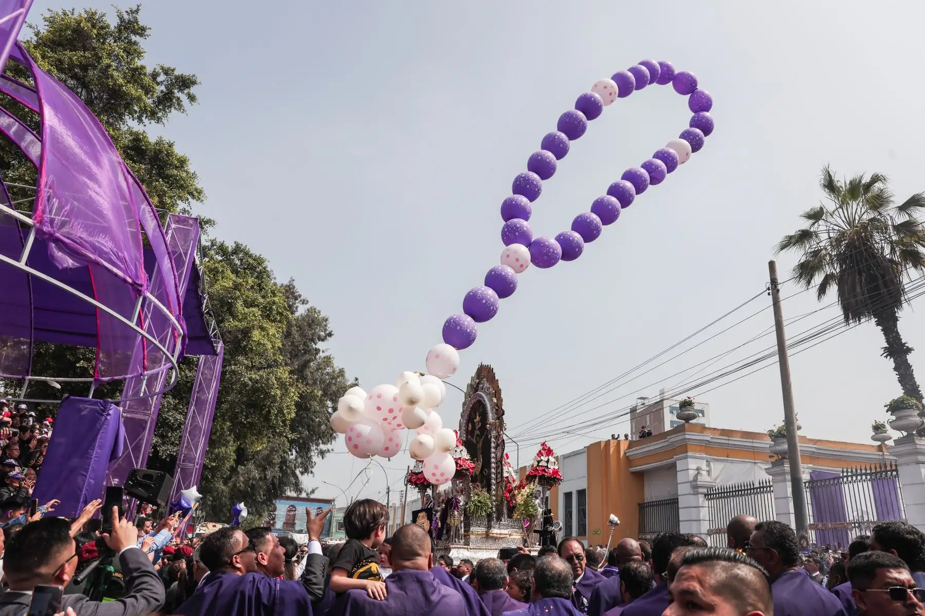 Fieles elevan al cielo un conjunto de globos en forma de rosario, frente al hospital Dos de Mayo, rindiendo homenaje al Señor de los Milagros. Foto: ANDINA/ Connie Calderon