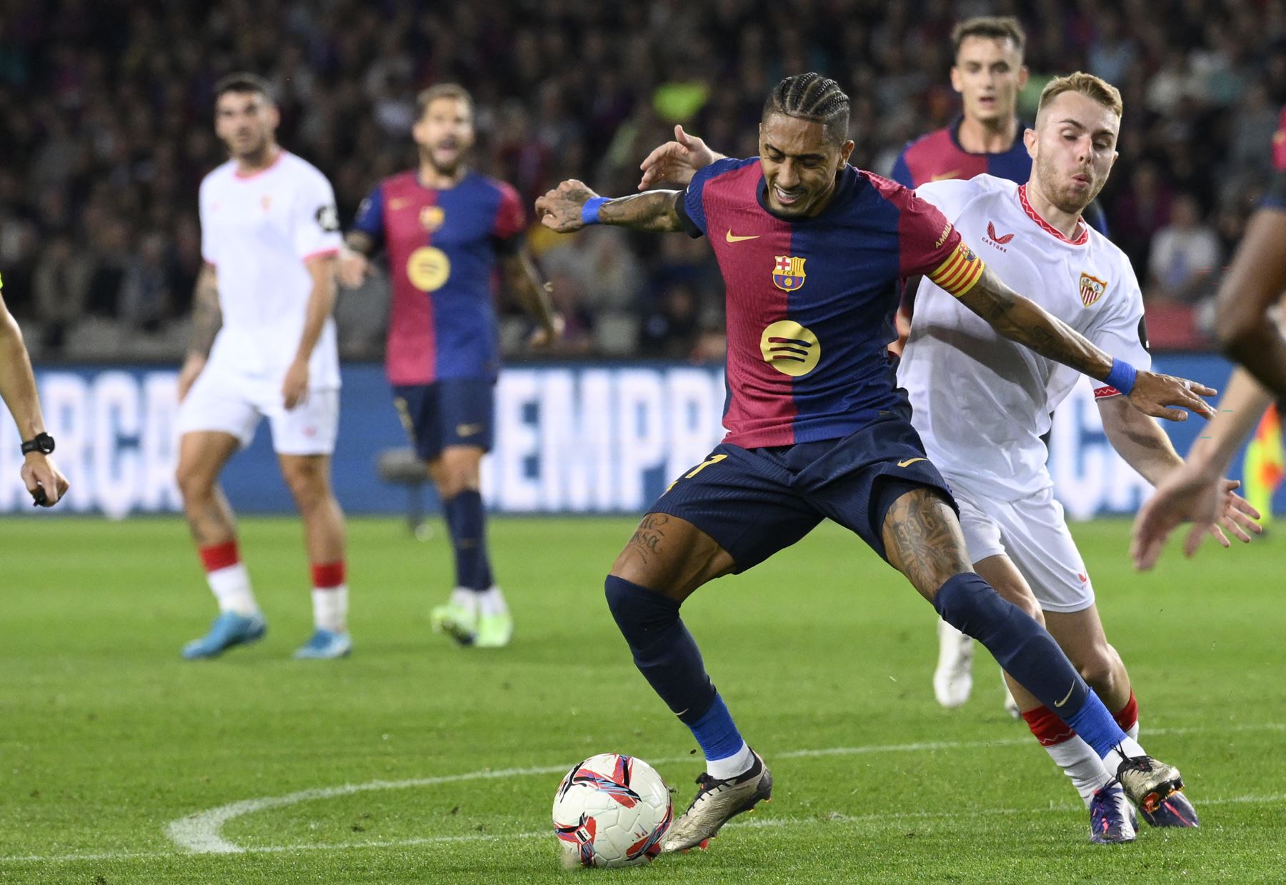 El delantero español del Sevilla Peque  comete faltas el delantero brasileño del Barcelona Raphinha durante el partido de fútbol de la liga española entre el FC Barcelona y el Sevilla FC. AFP