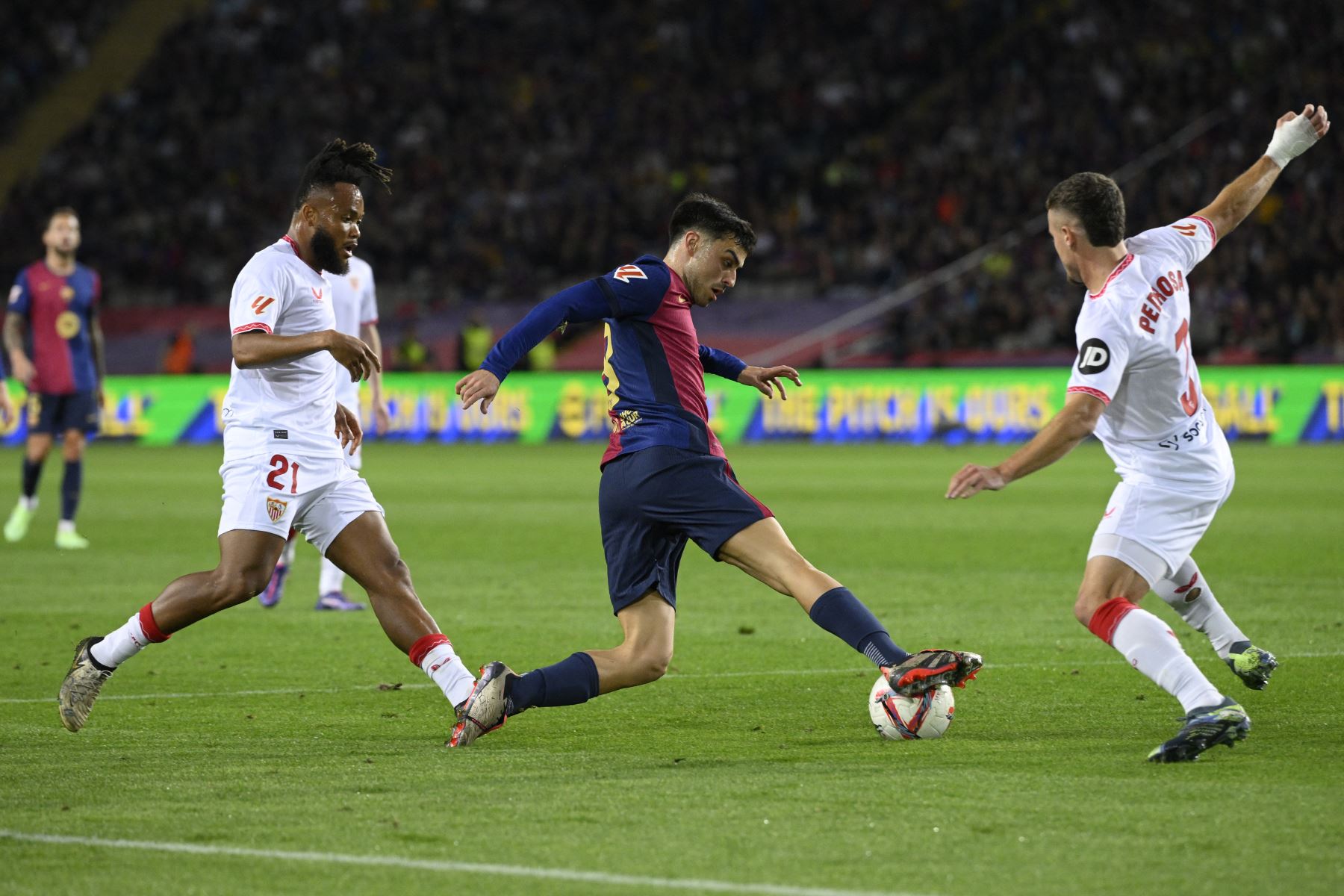 El delantero nigeriano del Sevilla  Chidera Ejuke, el centrocampista español del Barcelona Pedri y el defensor español del Sevilla Adria Pedrosa compiten por el balón durante el partido de fútbol de la liga española entre el FC Barcelona y el Sevilla FC. AFP