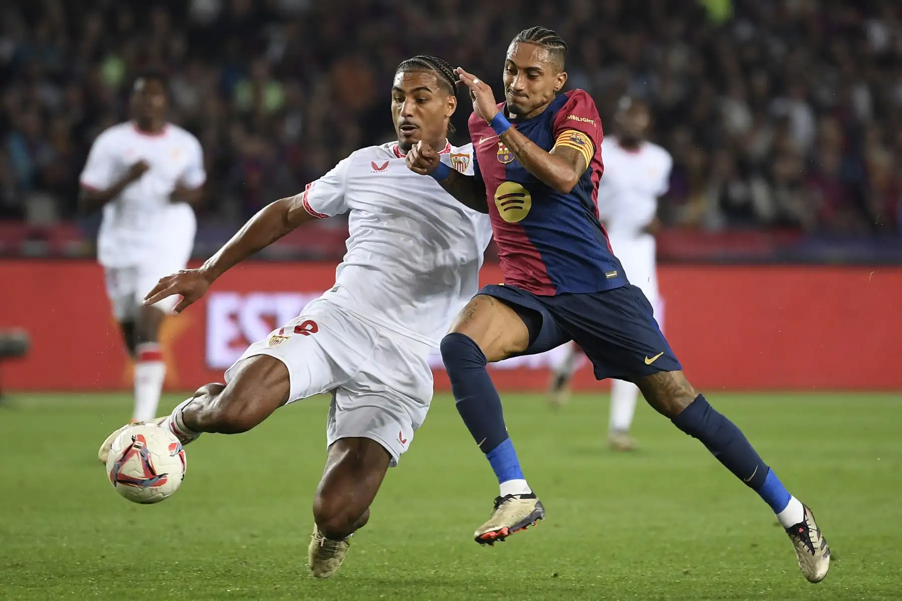 El defensa francés del Sevilla, Loic Bade, y el delantero brasileño del Barcelona, ​​Raphinha, compiten por el balón durante el partido de fútbol de la liga española entre el FC Barcelona y el Sevilla FC en el Estadi Olimpic Lluis Companys en Barcelona. Foto.: ANDINA/AFP