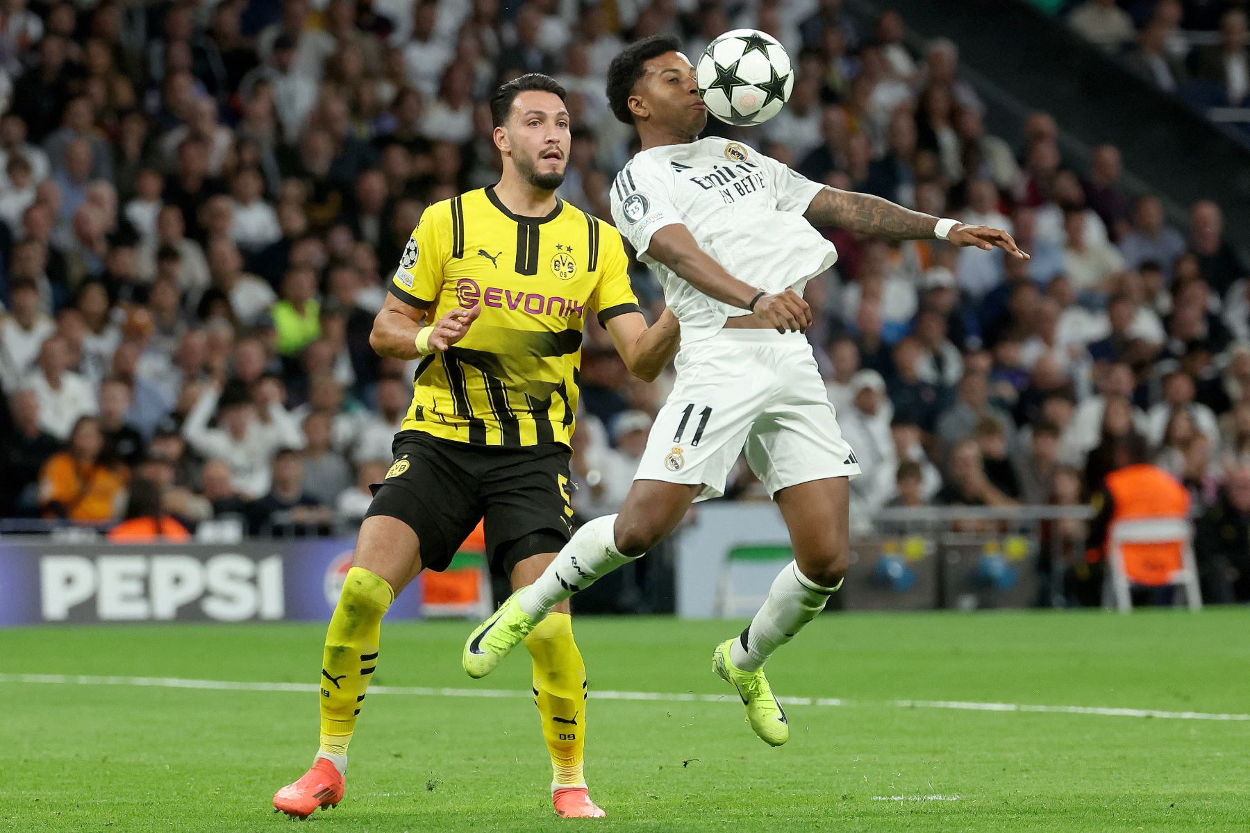 El delantero brasileño del Real Madrid  Rodrygo  controla el balón desafiado por el defensor argelino del Borussia Dortmund  Rami Bensebaini durante la Liga de Campeones de la UEFA, fase liguera del partido de fútbol del día 3 entre el Real Madrid CF y el Borussia Dortmund. AFP