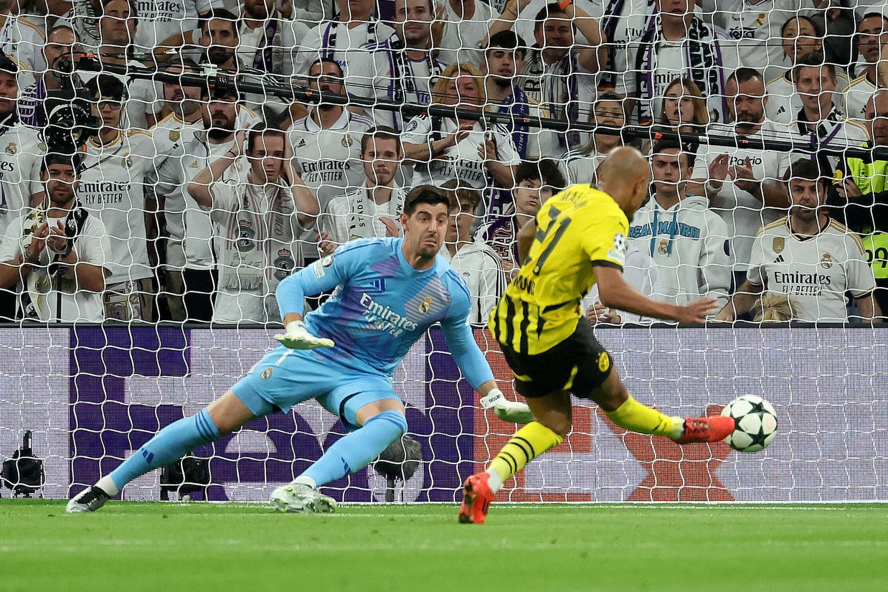 El delantero holandés del Borussia Dortmund  Donyell Malen anota un gol ante el portero belga del Real Madrid  Thibaut Courtois durante la Liga de Campeones de la UEFA, fase liguera del partido de fútbol del día 3 entre el Real Madrid CF y el Borussia Dortmund. AFP