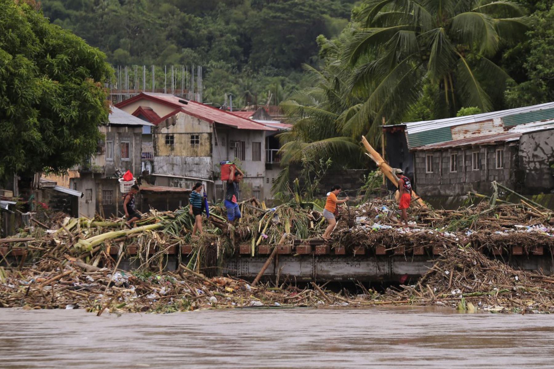 Los residentes cruzan un puente lleno de escombros debido a las fuertes lluvias provocadas por la tormenta tropical Trami en la ciudad de Polangui, provincia de Albay, al sur de Manila. Foto AFP