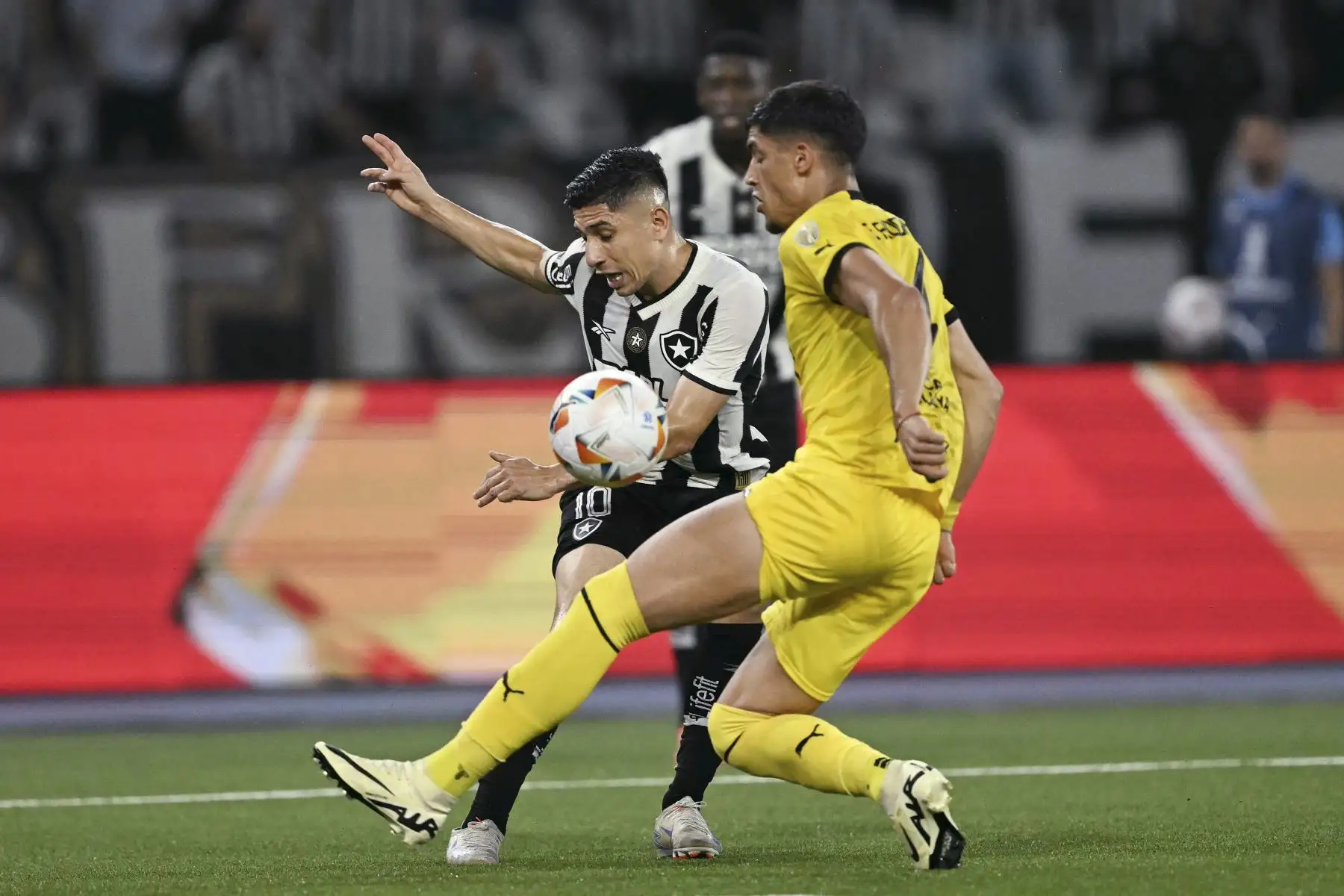 El delantero venezolano de Botafogo, Jefferson Savarino, y el defensa de Peñarol, Guzmán Rodríguez, luchan por el balón durante el partido de ida de las semifinales de la Copa Libertadores entre el Botafogo de Brasil y el Peñarol de Uruguay en el estadio Olímpico Nilton Santos en Río de Janeiro, Brasil. Foto: ANDINA/AFP