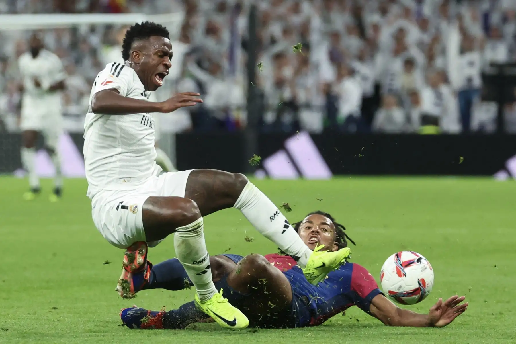 El delantero brasileño del Real Madrid, Vinicius Junior, choca con el defensa francés del Barcelona, ​​Jules Kounde, durante el partido de fútbol de la liga española entre el Real Madrid CF y el FC Barcelona en el estadio Santiago Bernabéu de Madrid. Foto: ANDINA/AFP