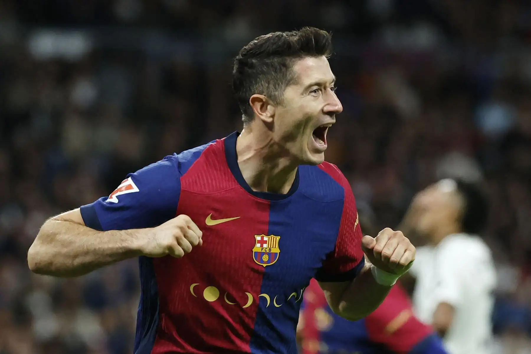 El delantero polaco del Barcelona, ​​Robert Lewandowski, celebra el segundo gol de su equipo durante el partido de fútbol de la liga española entre el Real Madrid CF y el FC Barcelona en el estadio Santiago Bernabéu de Madrid. Foto: ANDINA/AFP.