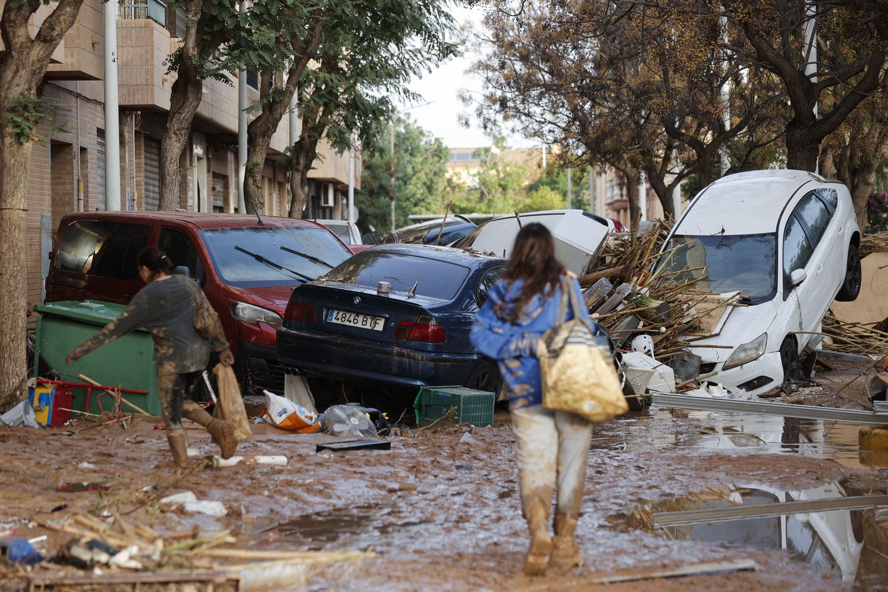 Varias personas caminan entre el lodo acumulado en las calles a causa de las intensas lluvias caídas por la fuerte dana, este jueves en Catarroja. Catarroja, una de las localidades afectadas por la dana que asoló este martes la provincia de Valencia, se afana por restablecer los suministros cortados a consecuencia del temporal y en ofrecer ayuda humanitaria a los vecinos. Foto: EFE