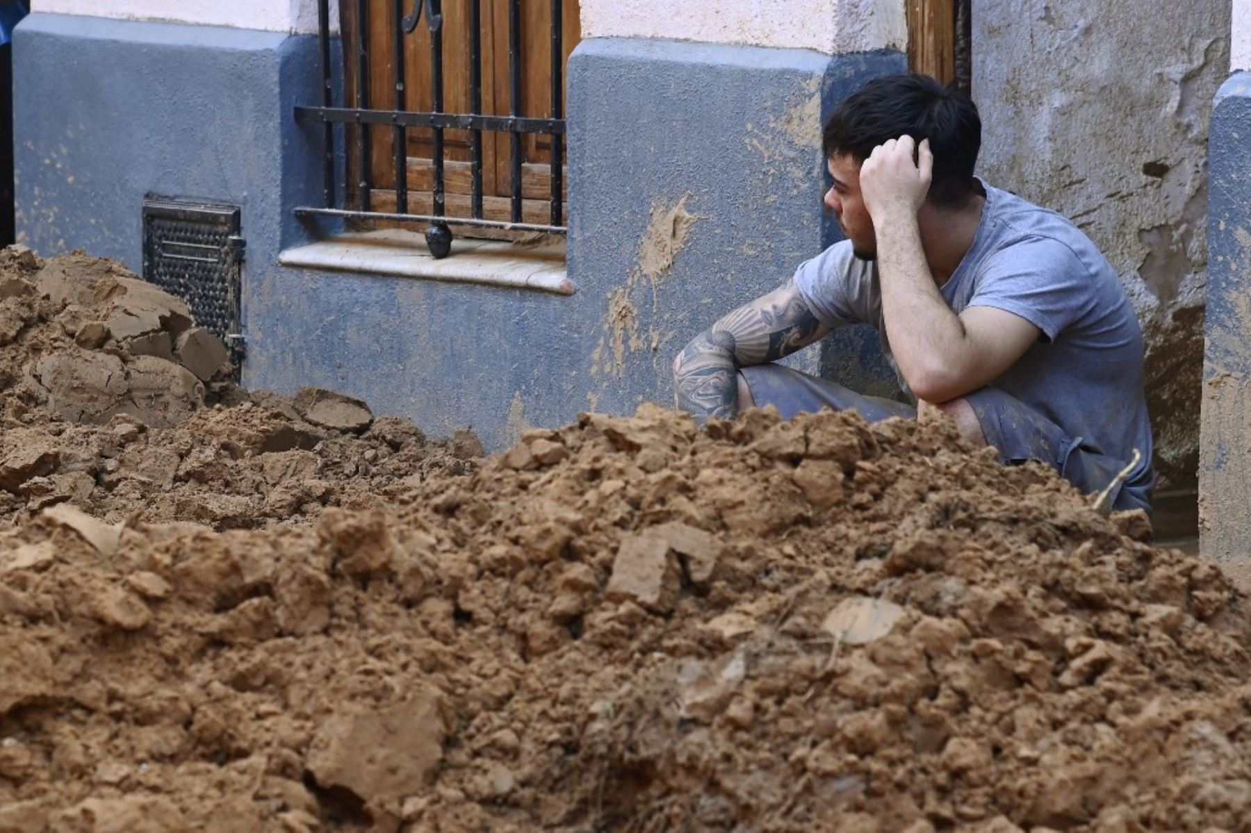 Un hombre sentado detrás de una gran pila de barro el 1 de noviembre de 2024, tras los devastadores efectos de las inundaciones en la ciudad de Paiporta, en la región de Valencia, al este de España. El número de muertos por las peores inundaciones sufridas en una generación asciende a 205. Foto: AFP