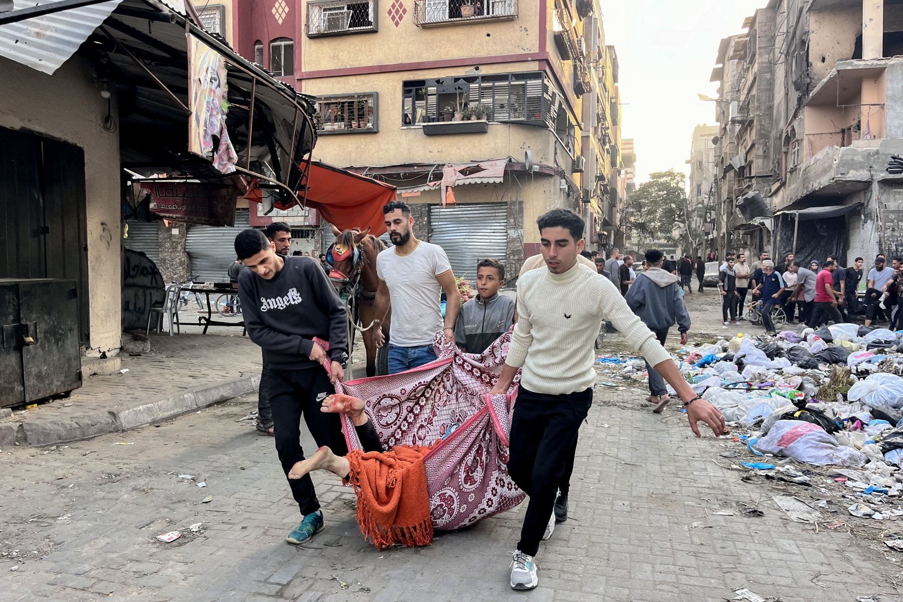 Hombres llevan un cuerpo dentro de una manta en Beit Lahia, en el norte de la Franja de Gaza, en medio de la guerra en curso entre Israel y el movimiento palestino Hamás. Foto: AFP/Archivo