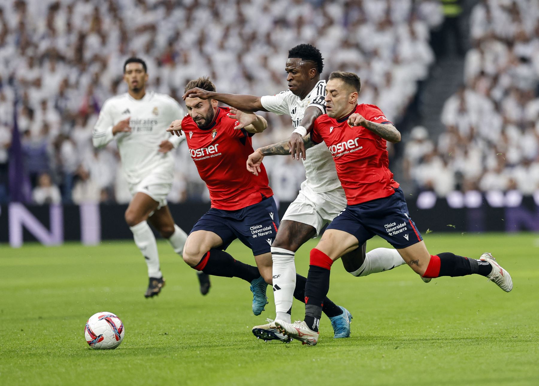 El delantero brasileño del Real Madrid  Vinicius Junior  es desafiado por el defensor español de Osasuna  Rubén Peña  y el centrocampista español de Osasuna  Jon Moncaloya durante el partido de fútbol de la liga española entre el Real Madrid CF y el CA Osasuna. AFP