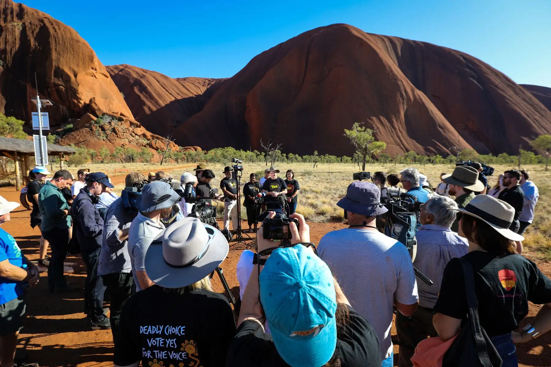 El primer ministro australiano, Anthony Albanese  junto al activista por los derechos indígenas Noel Pearson y la ministra principal del Territorio del Norte, Natasha Fyles, mientras habla con los medios de comunicación en la base de Uluru, también conocida como Ayers Rock, en el Parque Nacional Uluru Kata Tjuta, en el centro de Australia. el 11 de octubre de 2023. AFP