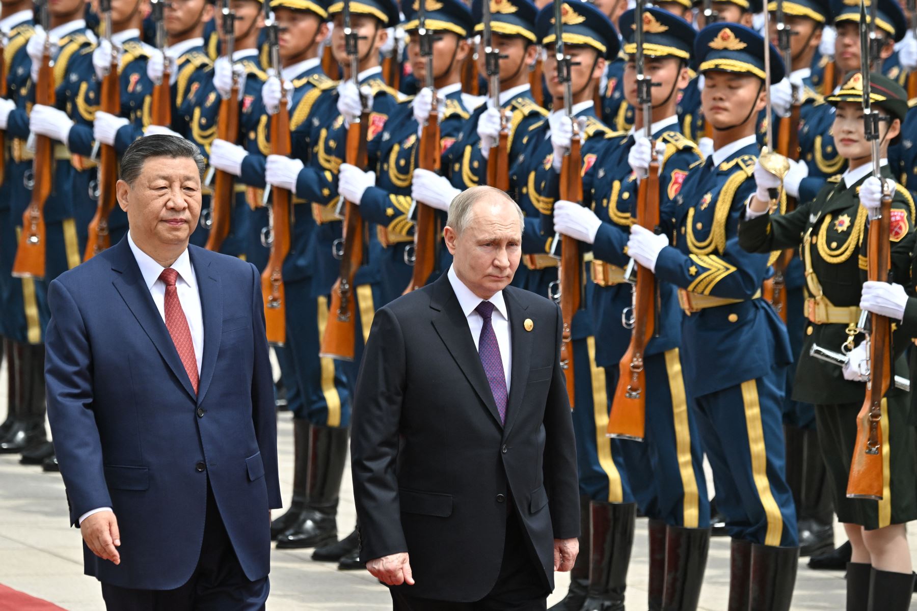 En esta fotografía de piscina distribuida por la agencia estatal rusa Sputnik, el presidente de Rusia, Vladimir Putin, y el presidente de China, Xi Jinping, asisten a una ceremonia oficial de bienvenida frente al Gran Salón del Pueblo en la Plaza de Tiananmen en Beijing el 16 de mayo de 2024. AFP