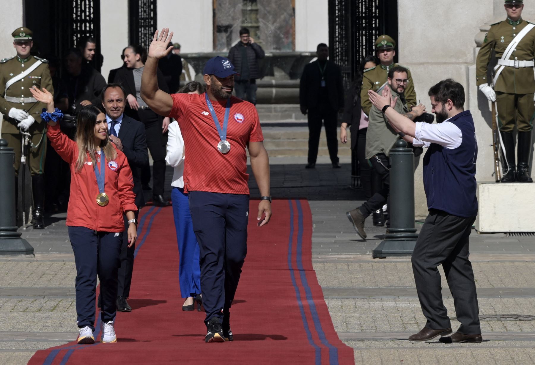 El presidente de Chile, Gabriel Boric, saluda a la medallista de oro olímpica femenina en skeet, Francisca Crovetto  y al medallista de plata grecorromano masculino de 130 kg, Yasmani Acosta, durante una ceremonia de bienvenida en el palacio presidencial de La Moneda, en Santiago, el 12 de agosto de 2024. AFP