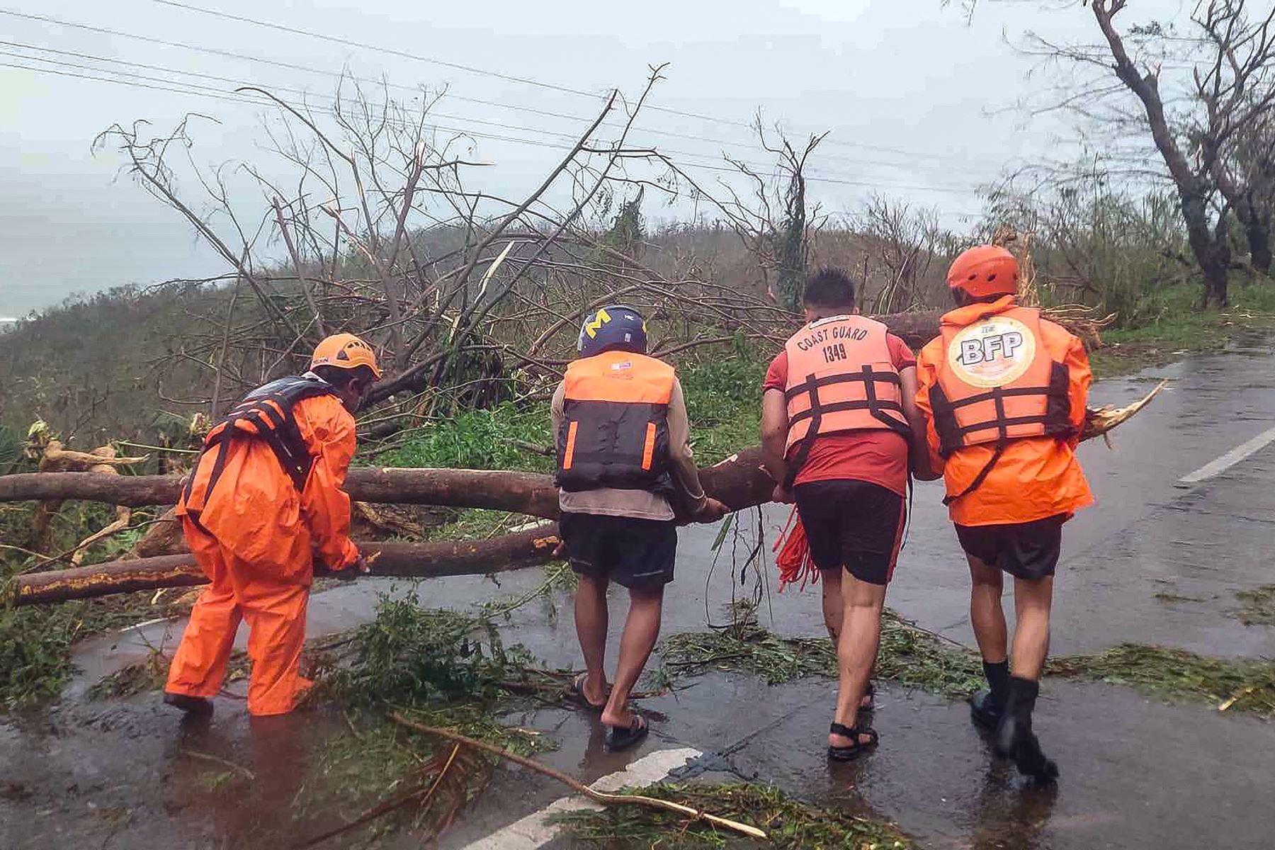 Esta fotografía tomada por la Guardia Costera de Filipinas (PCG) muestra al personal de la guardia costera limpiando una carretera de árboles caídos en la ciudad de Gigmoto, provincia de Catanduanes, al sur de Manila, después de que el súper tifón Man-yi azotara la provincia durante la noche. Foto: AFP