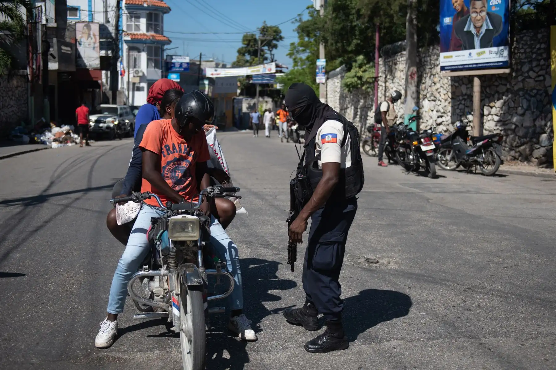 Un integrante de la Policía de Haití pide identificación a personas que transitan en una moto, en una calle de Puerto Príncipe (Haití). 
Foto: EFE
